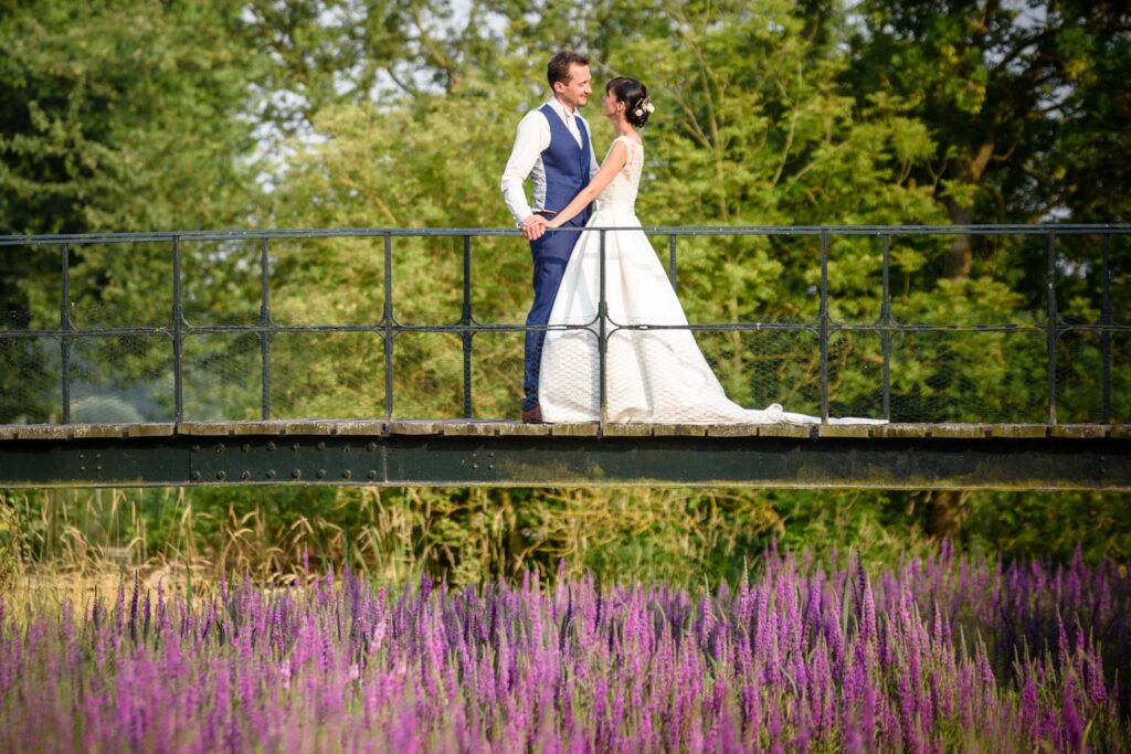 Bride and groom portrait on a bridge over purple flowers