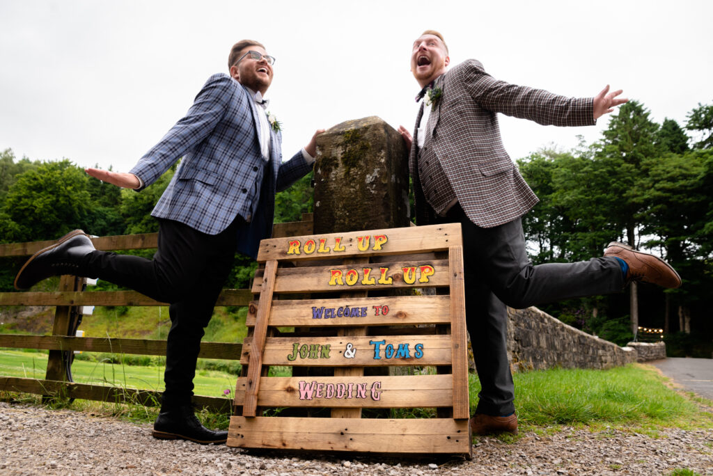 Grooms posing in front of their wedding sign