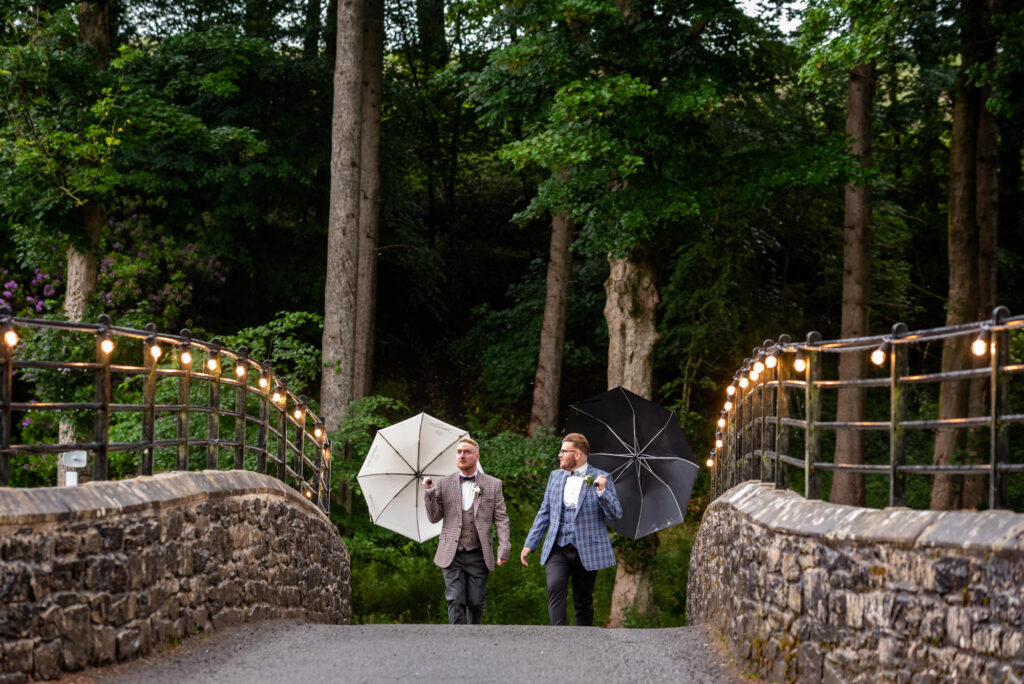 Grooms walking over the bridge towards the wedding site at Gisburn Park Estate