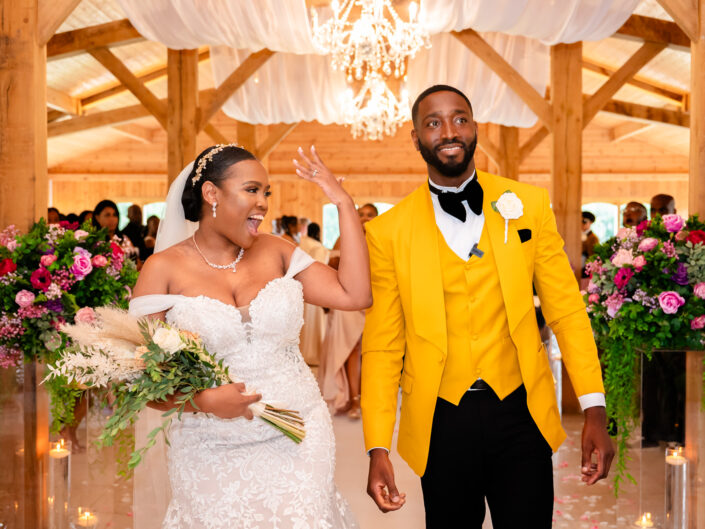 Bride and groom walking down the aisle at Merry dale Manor. The bride is showing her ring