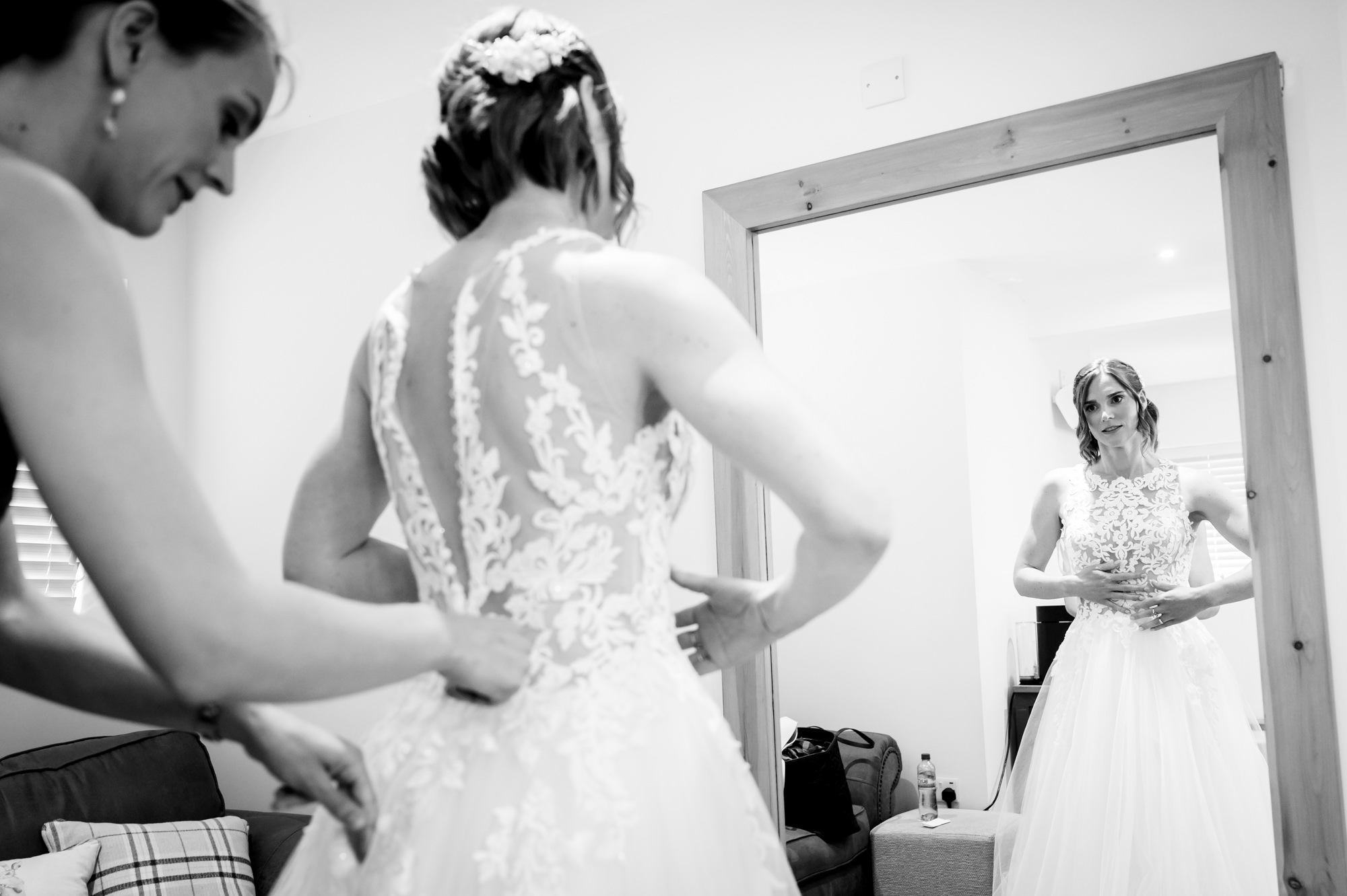 Bridesmaid helping the bride in her dress at Hanbury Wedding Barn