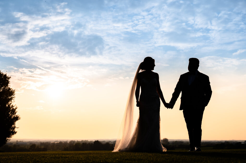 Bride and groom holding hands in the sunset at West Tower