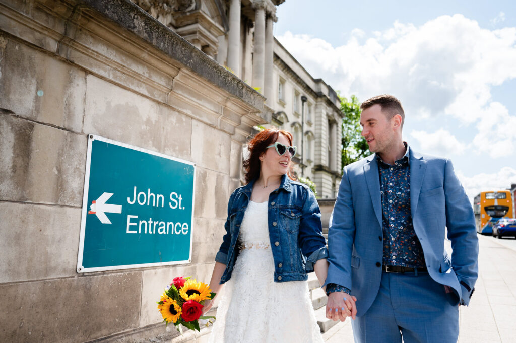 Bride and groom walking down the A6 outside Stockport Town Hall