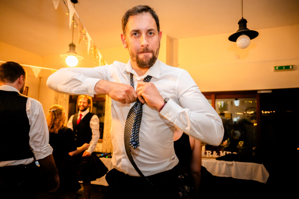 guest taking off his tie while dancing at The Roman Lakes