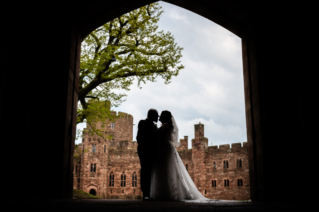 Bride and Groom's silouhette under the main entrance at Peckforton Castle