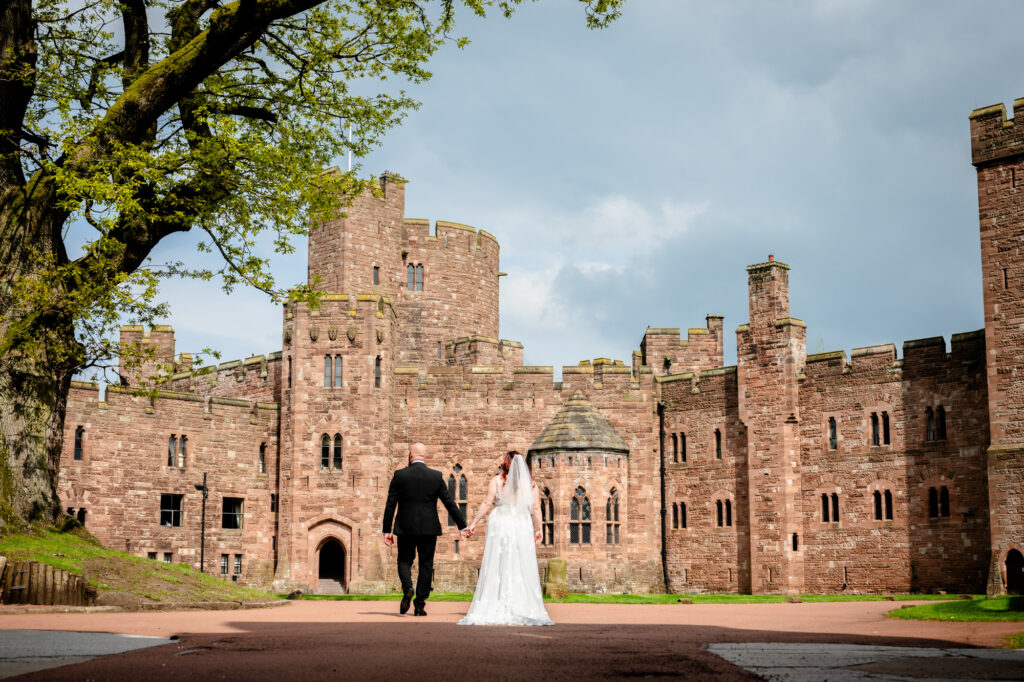 Bride and groom walking towards Peckforton Castle