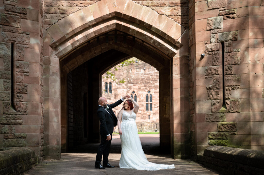 Bride and groom practising their first dance out side the main gate at Peckforton Castle