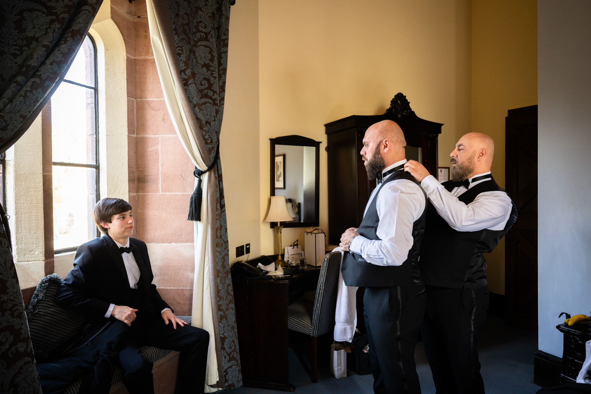 Groom's brother helping the groom to get dressed at Peckforton Castle