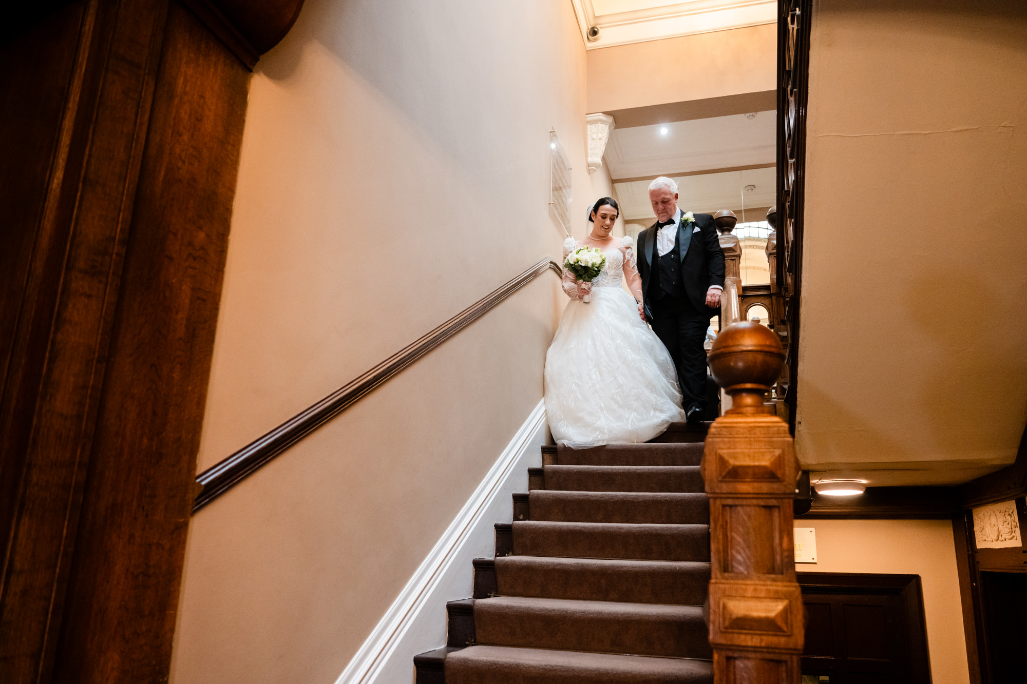 Bride walking down the stairs with her dad at West Tower