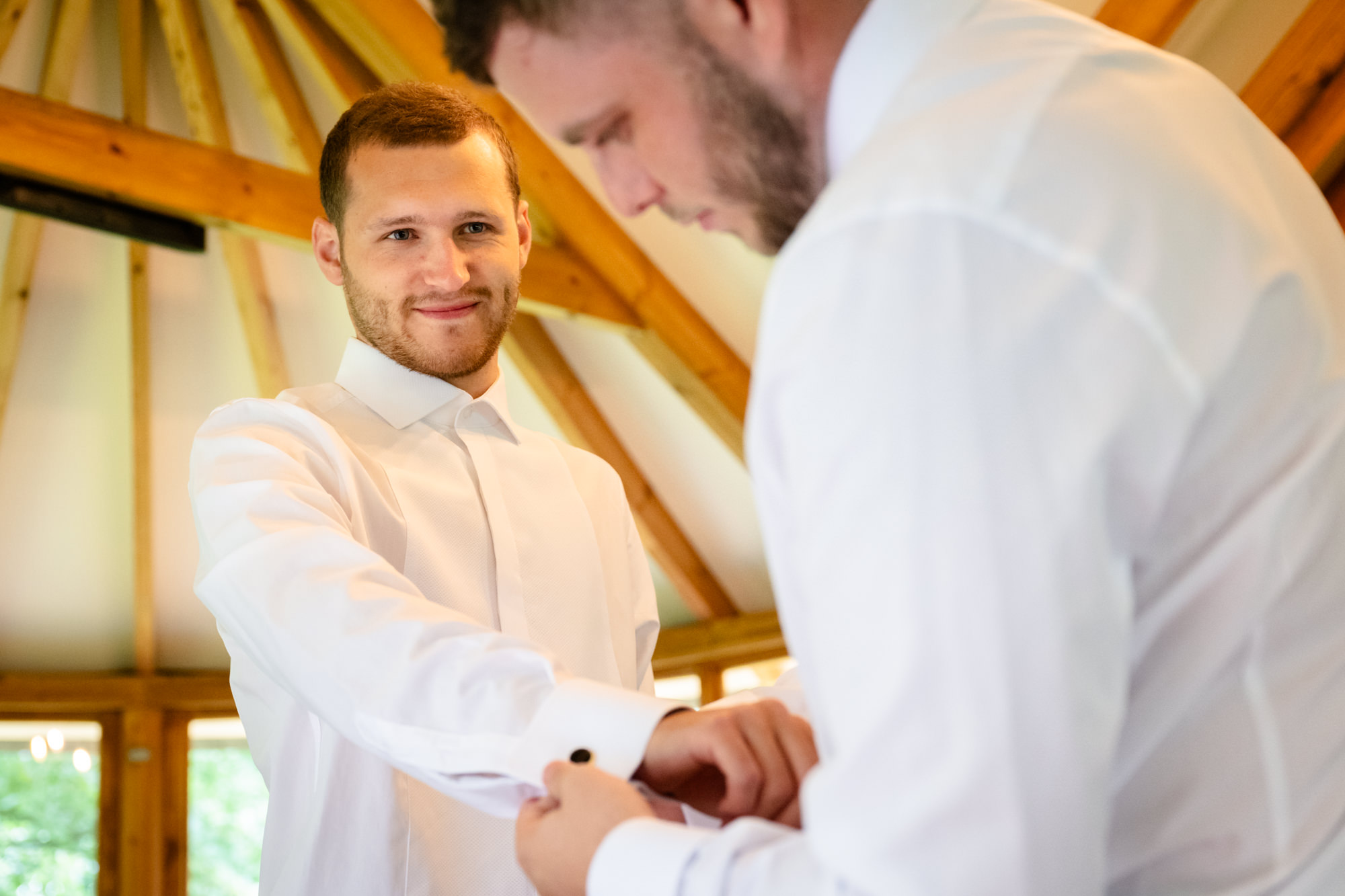 Best man helping the groom with his cufflinks 