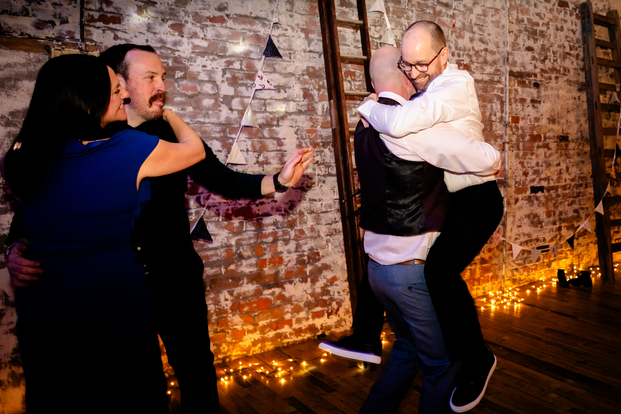 groom climbing on his friend on the dancefloorat Scale