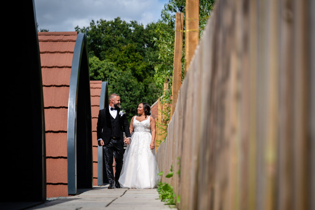 Bride and groom walking near the pods at Hanbury Barns