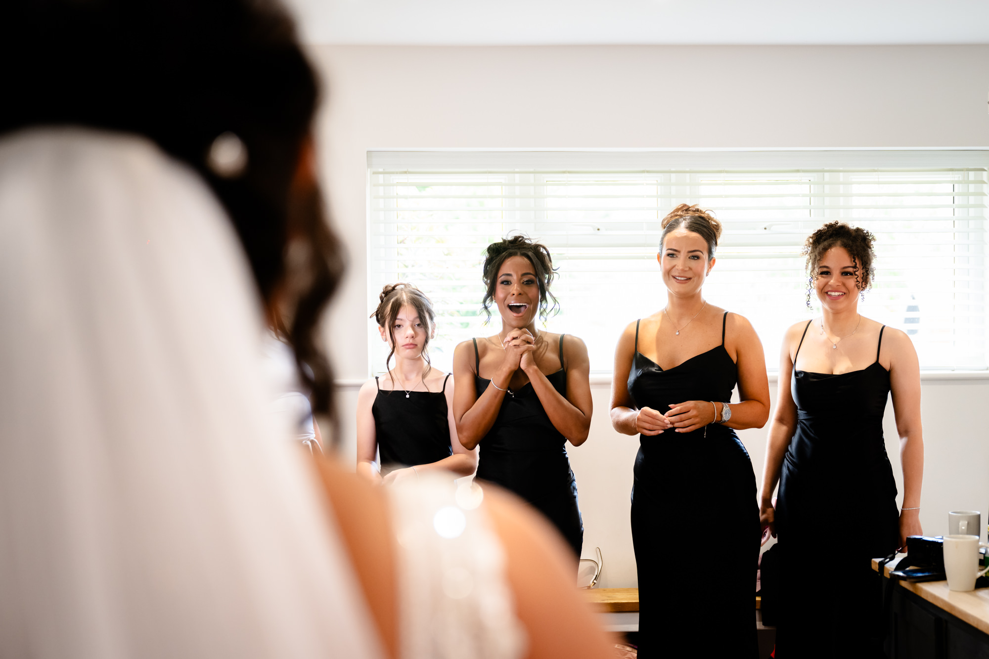 Bridesmaids in black dresses see the bride in her dress 