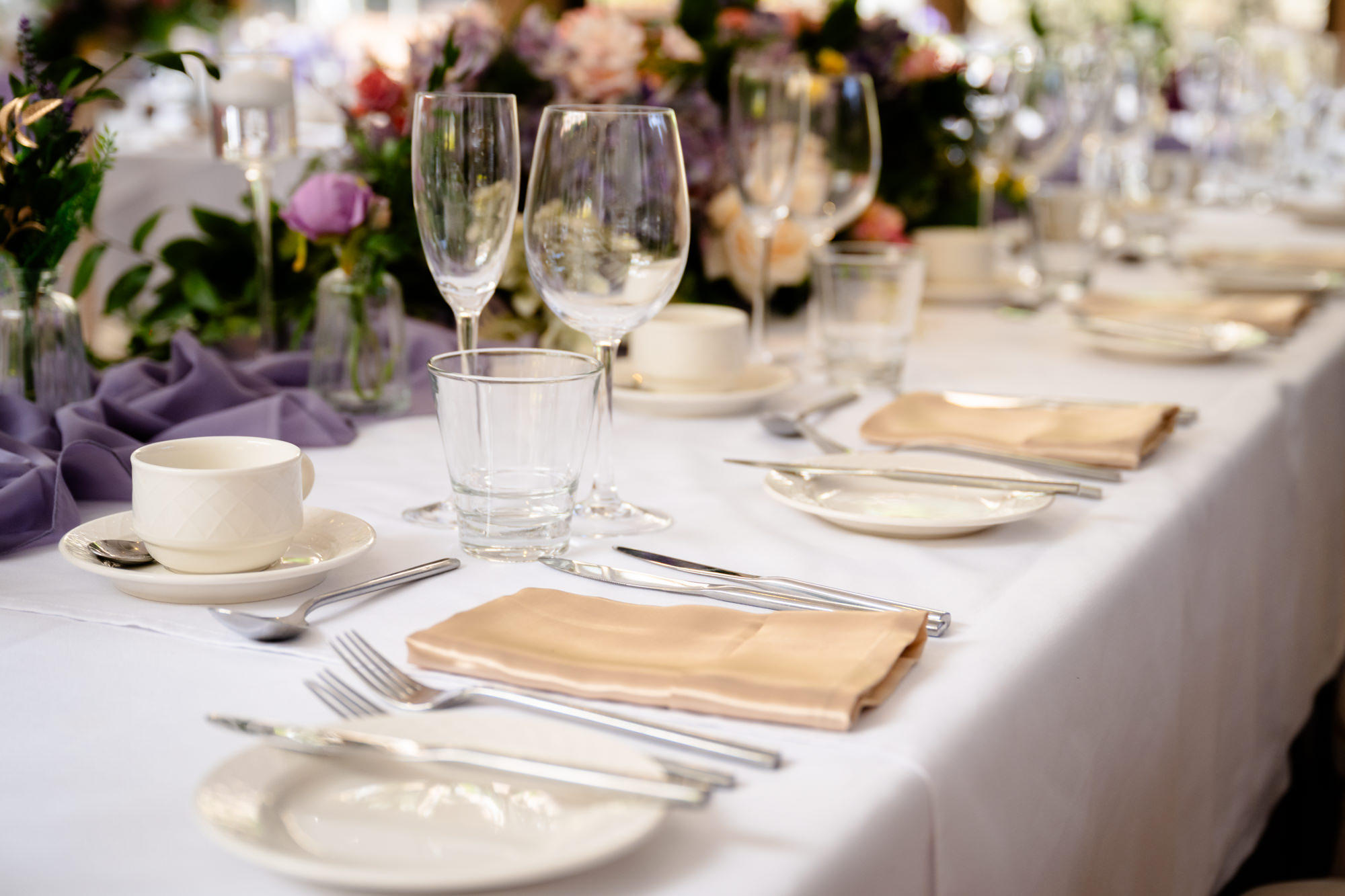 A wedding table setting at Moddershall Oaks with champagne flutes, plates, and orange napkins, ready for guests, with Disney's Tangled-themed wedding details.