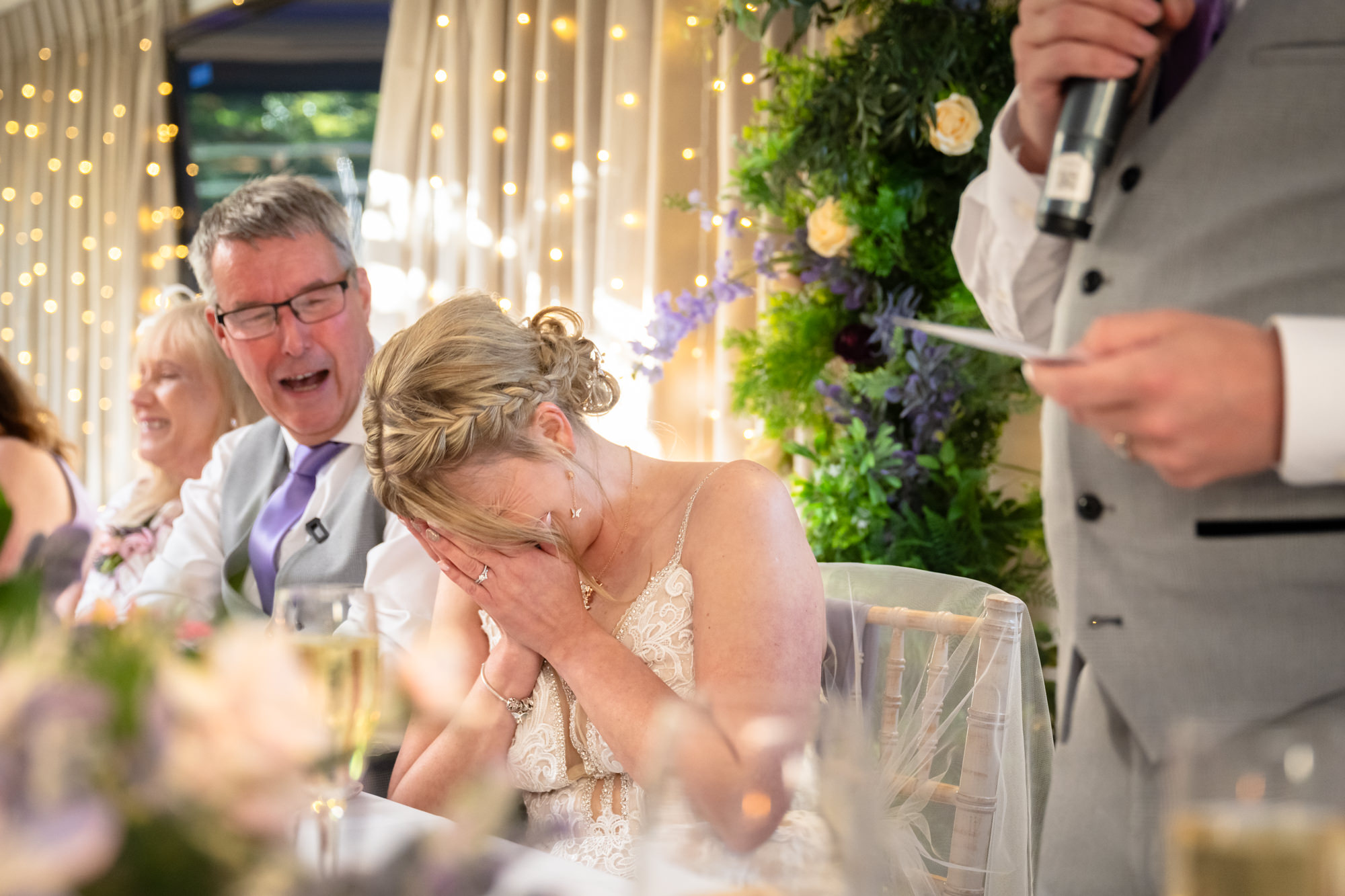 Bride laughing and hiding her face during the speeches