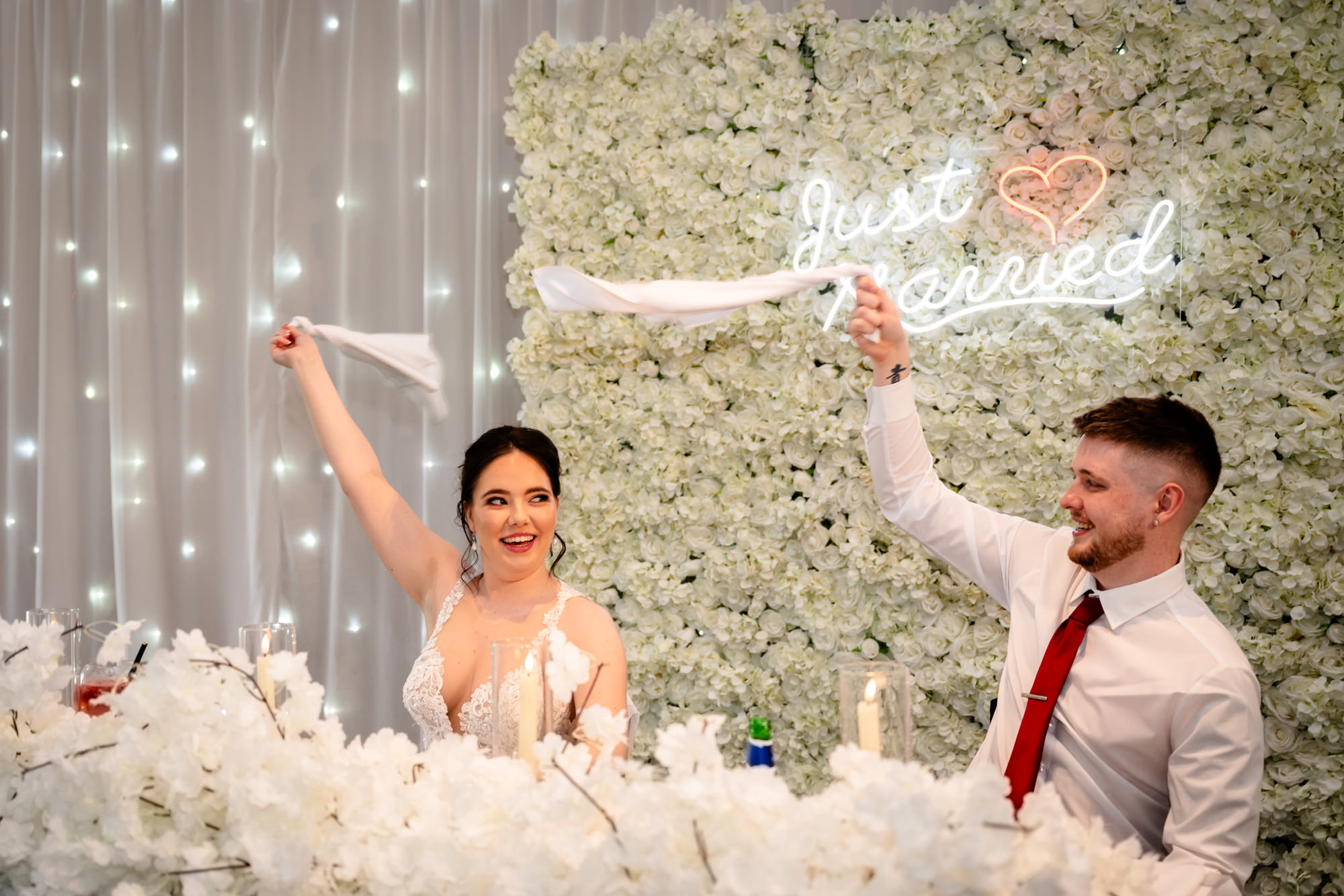 The bride and groom raise their arms in the air and celebrate during the wedding breakfast entertainment at Heaton House Farm.