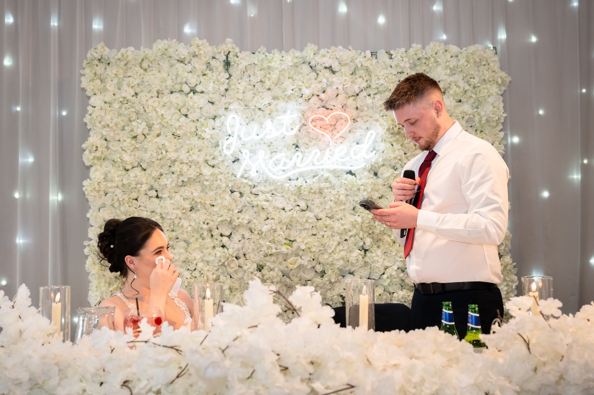 The groom is giving a speech while the bride looks on, in a photo taken at Heaton House Farm.