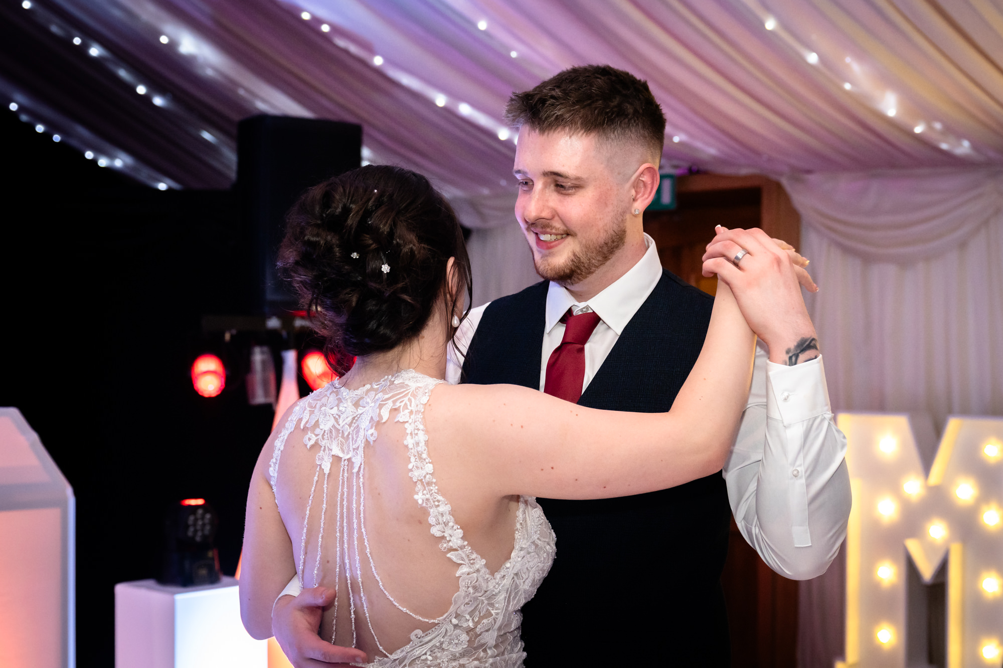 A close-up shot of the groom smiling as he dances with his new wife during their first dance at Heaton House Farm.