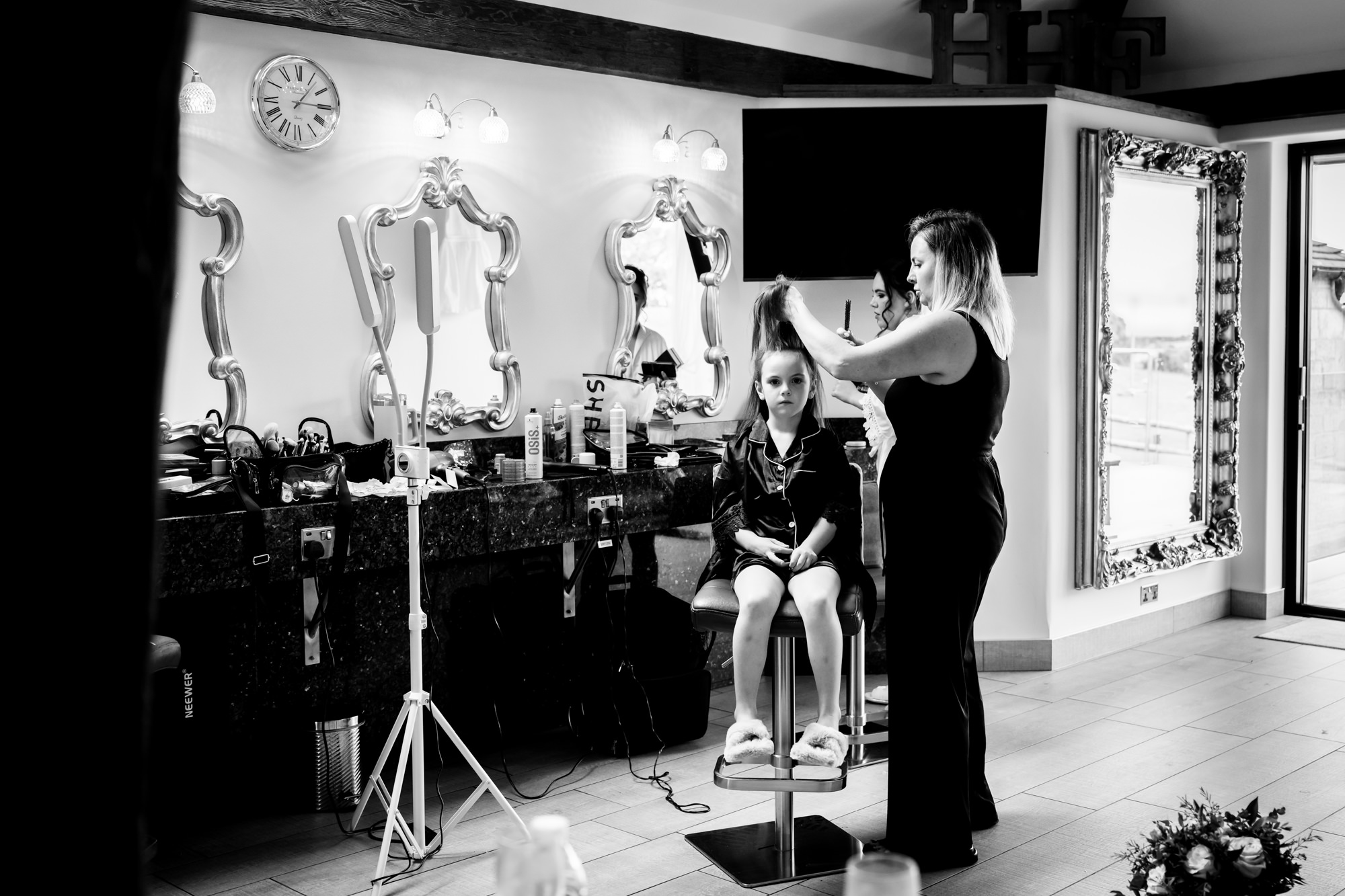 A black and white photo in the Pamper room shows a woman styling a young girl's hair while she sits on a high chair at Heaton House Farm.