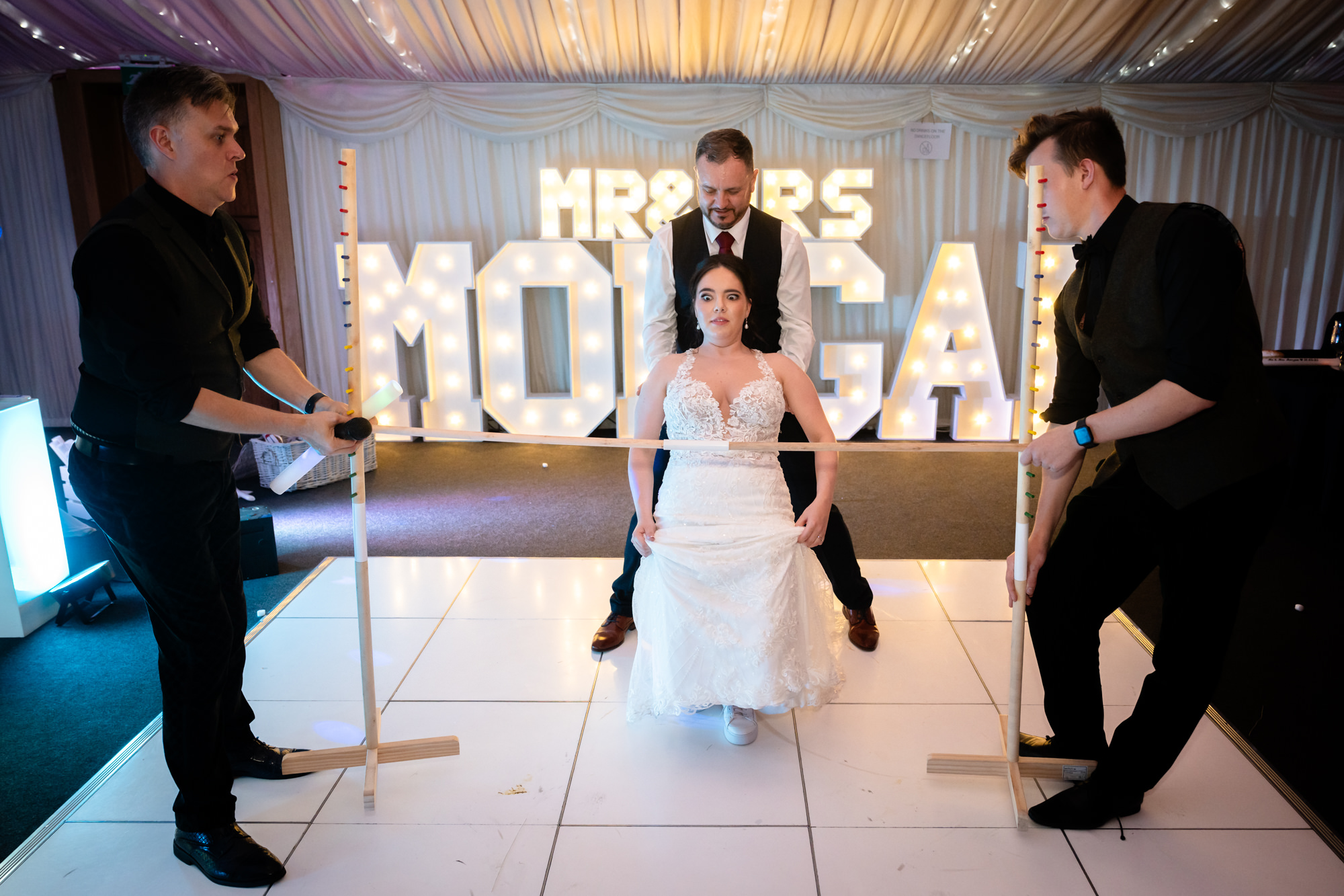 The bride is looking worried as she is about to limbo at the Heaton House Farm wedding party.