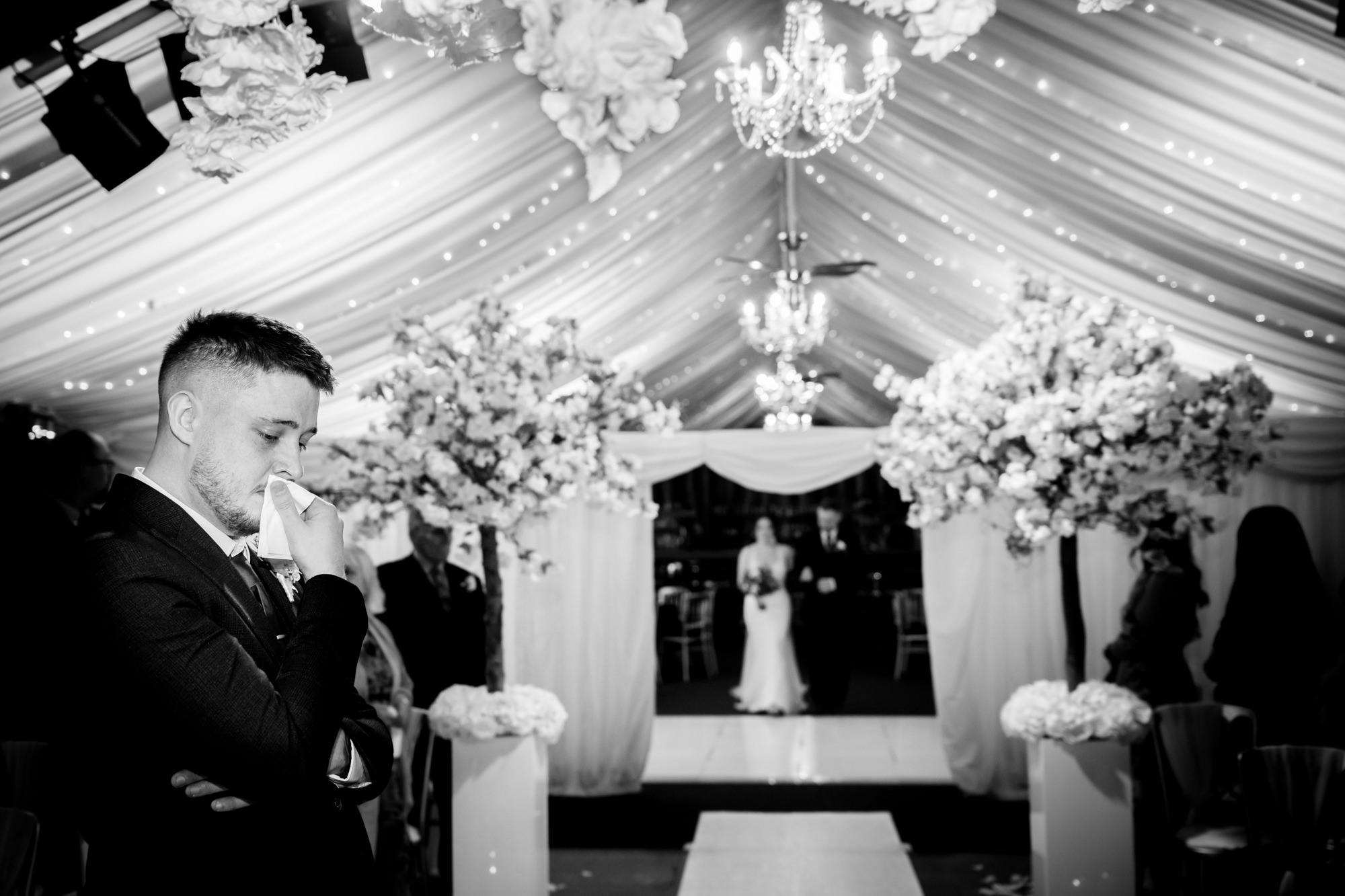 A black and white photo captures the emotional reaction of the groom during the wedding ceremony at Heaton House Farm.
