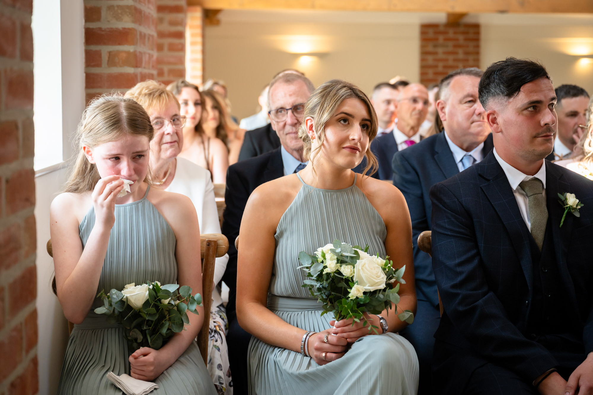 The bridesmaids sat on the front row. One of them is crying.