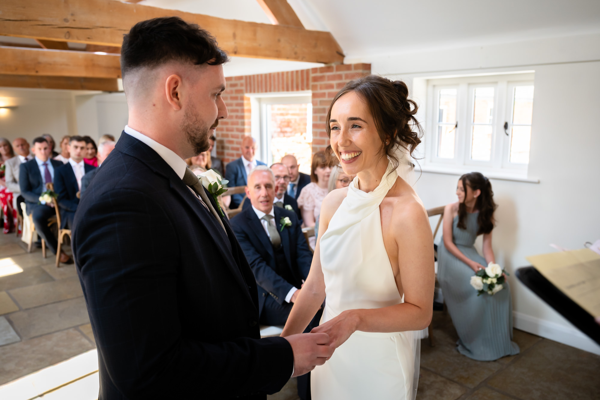 The bride and groom laugh together while standing at the altar during their wedding ceremony at Hanbury Barns.