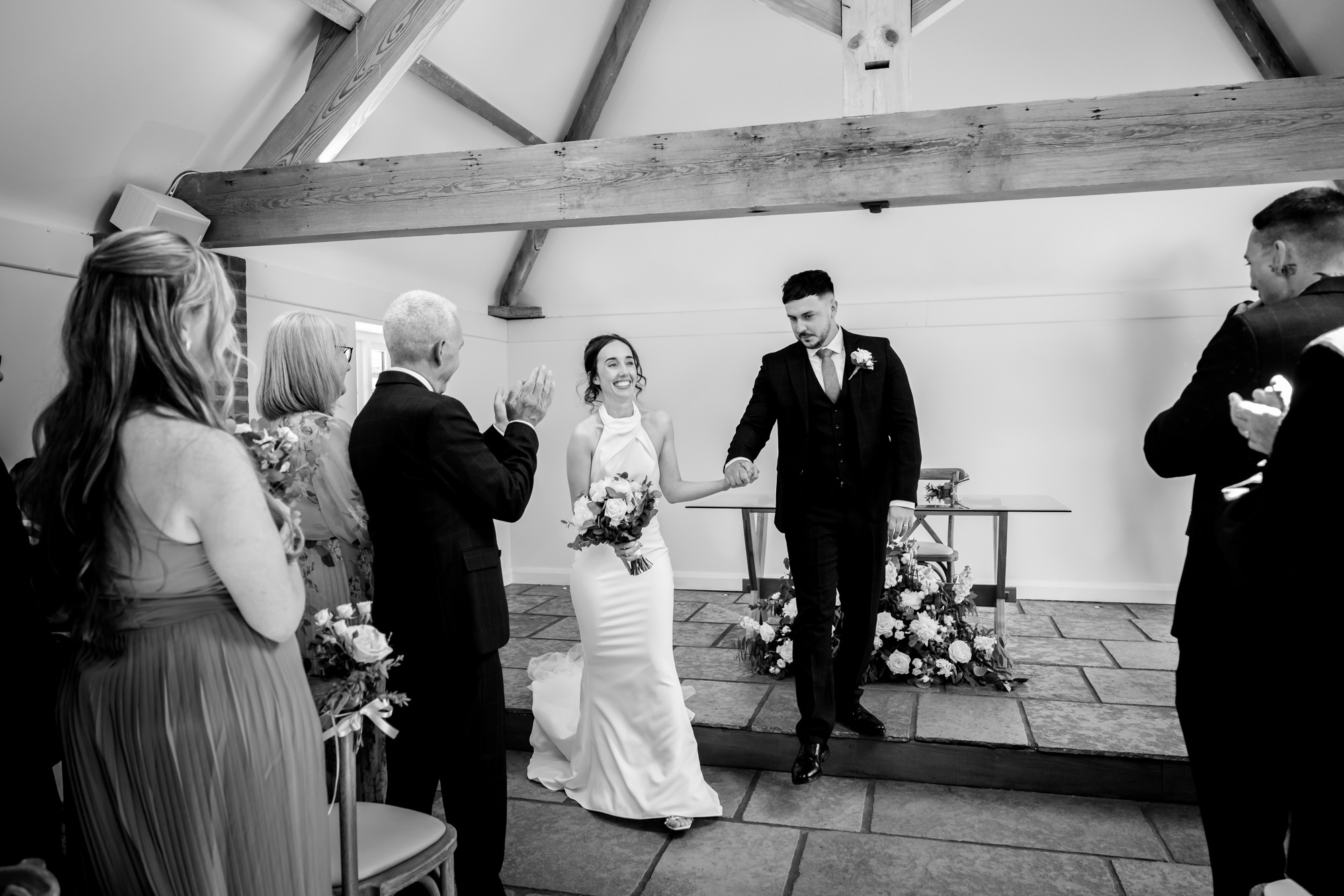 A black and white photo of the wedding ceremony at Hanbury Barns as the bride and groom are about to walk down the aisle