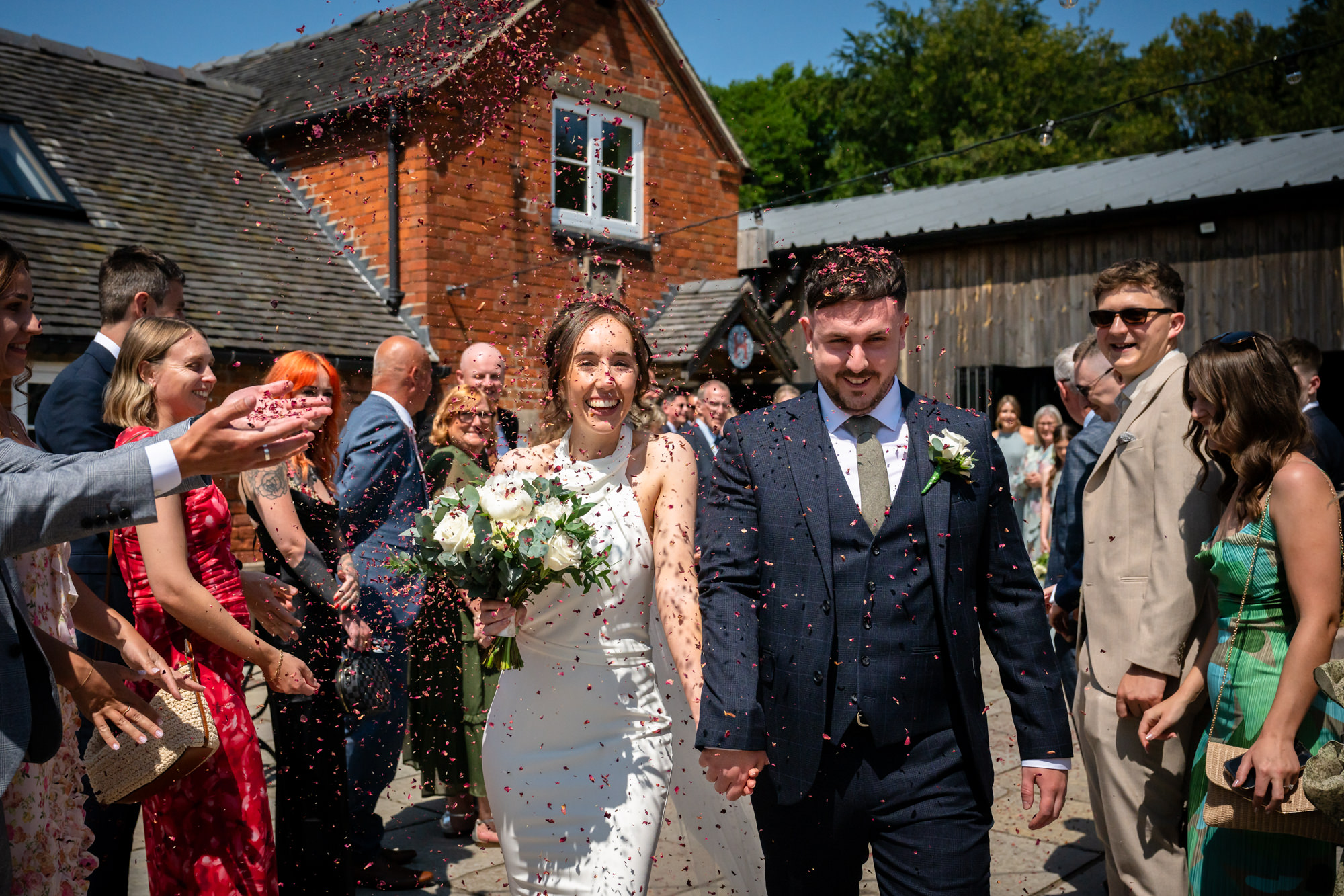 The bride and groom are showered with confetti as they exit the ceremony at Hanbury Barns.