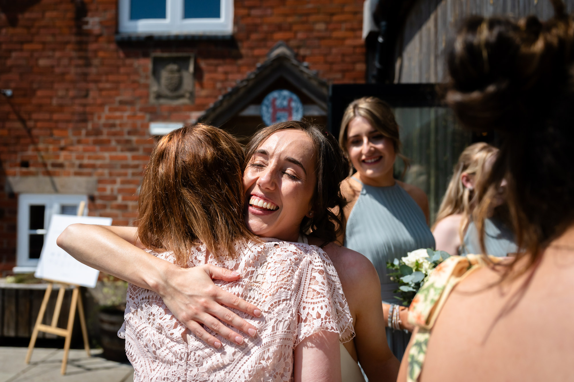 A candid shot of the bride receiving a hug from a guest at Hanbury Barns.