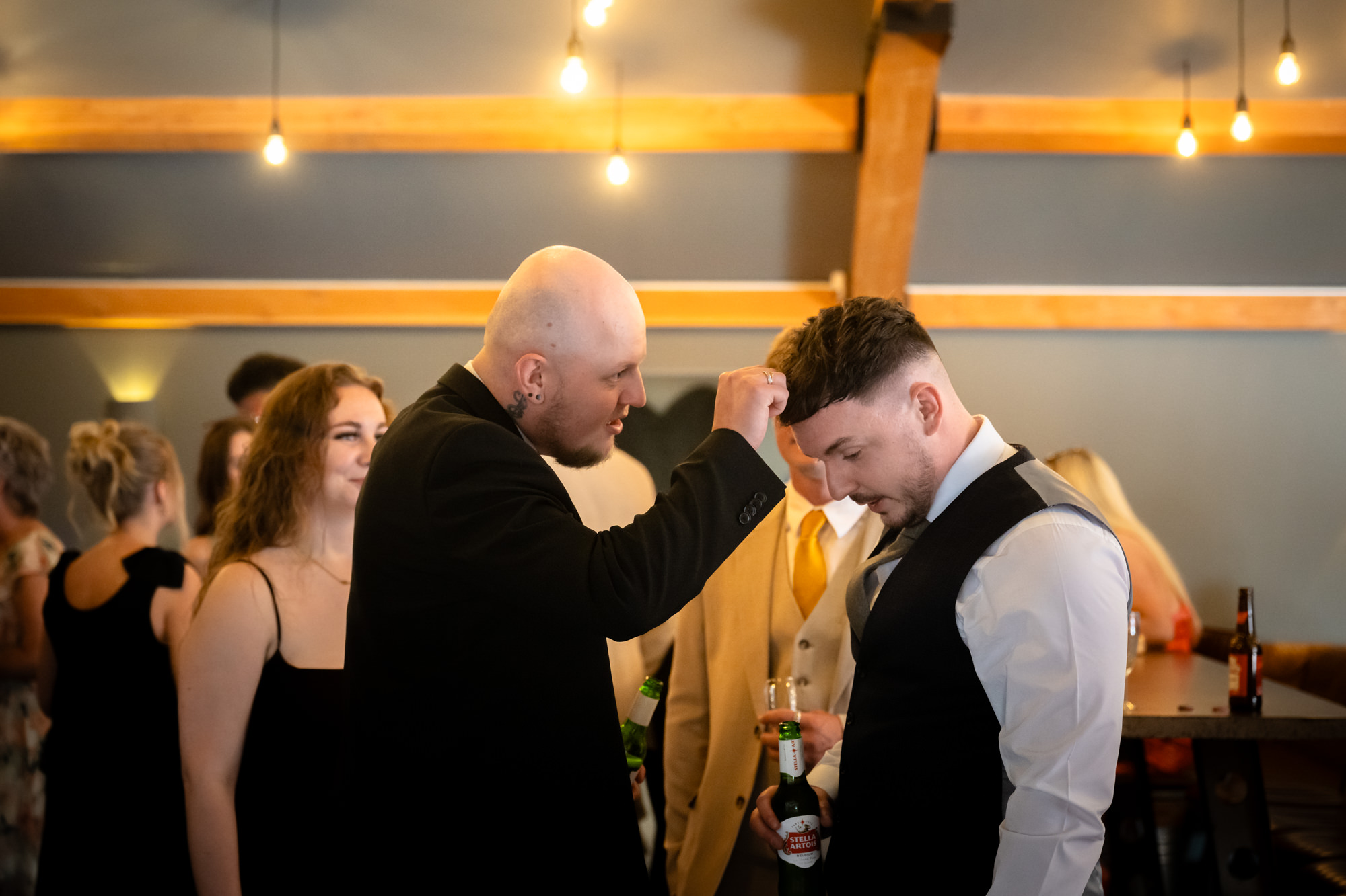 A guest is picking confetti from the groom's head