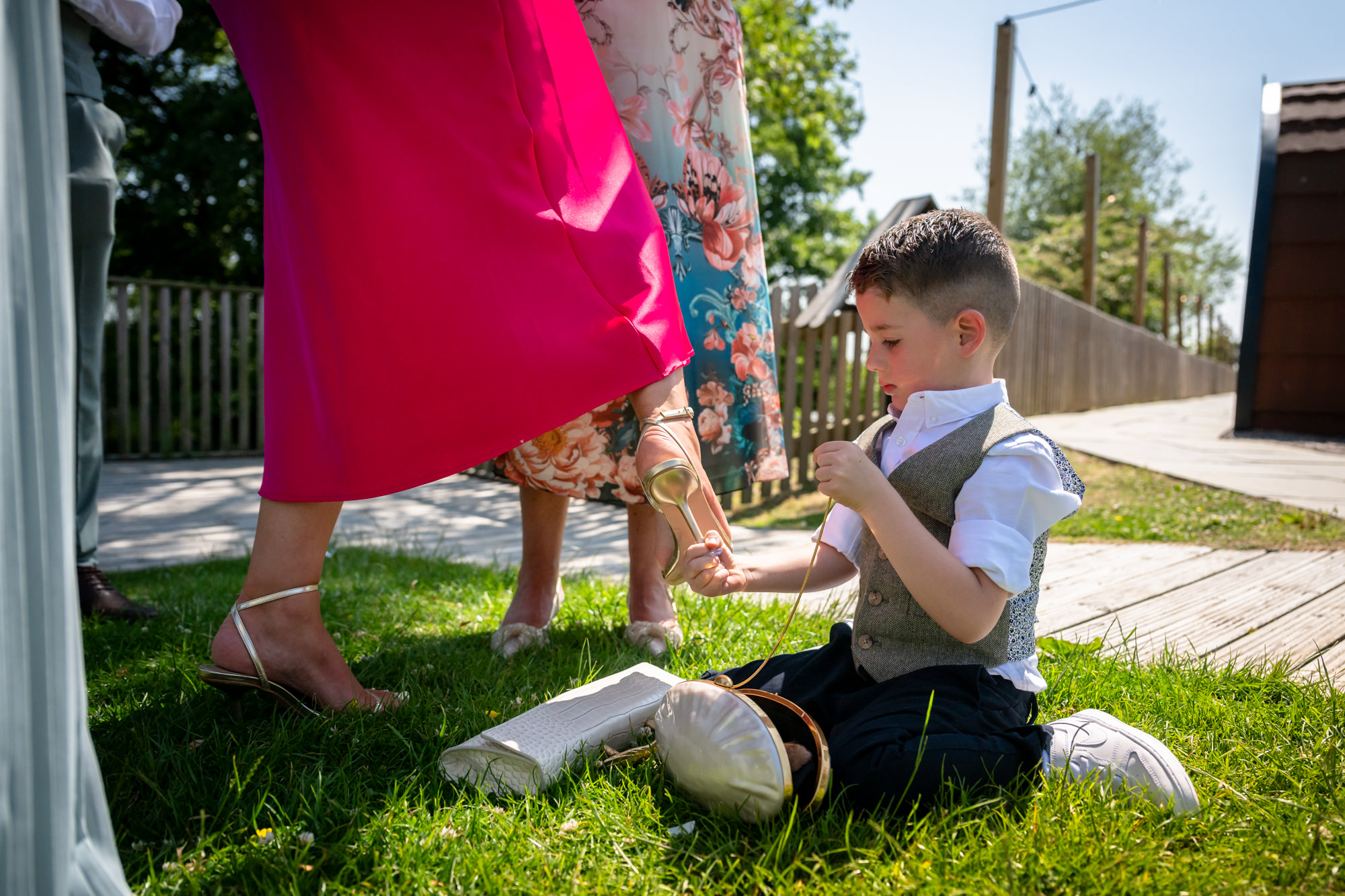 A boy is removing the heel cap from a lady's shoes a wedding at Hanbury Barns.