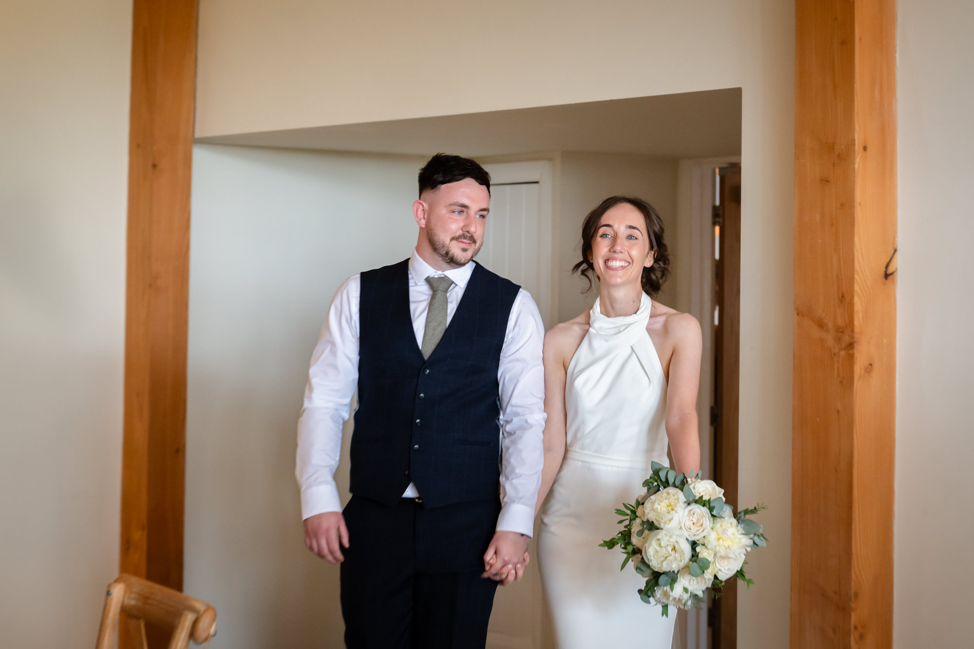 A photo from the wedding at Hanbury Barns of the bride and groom smiling as they enter the wedding breakfast.