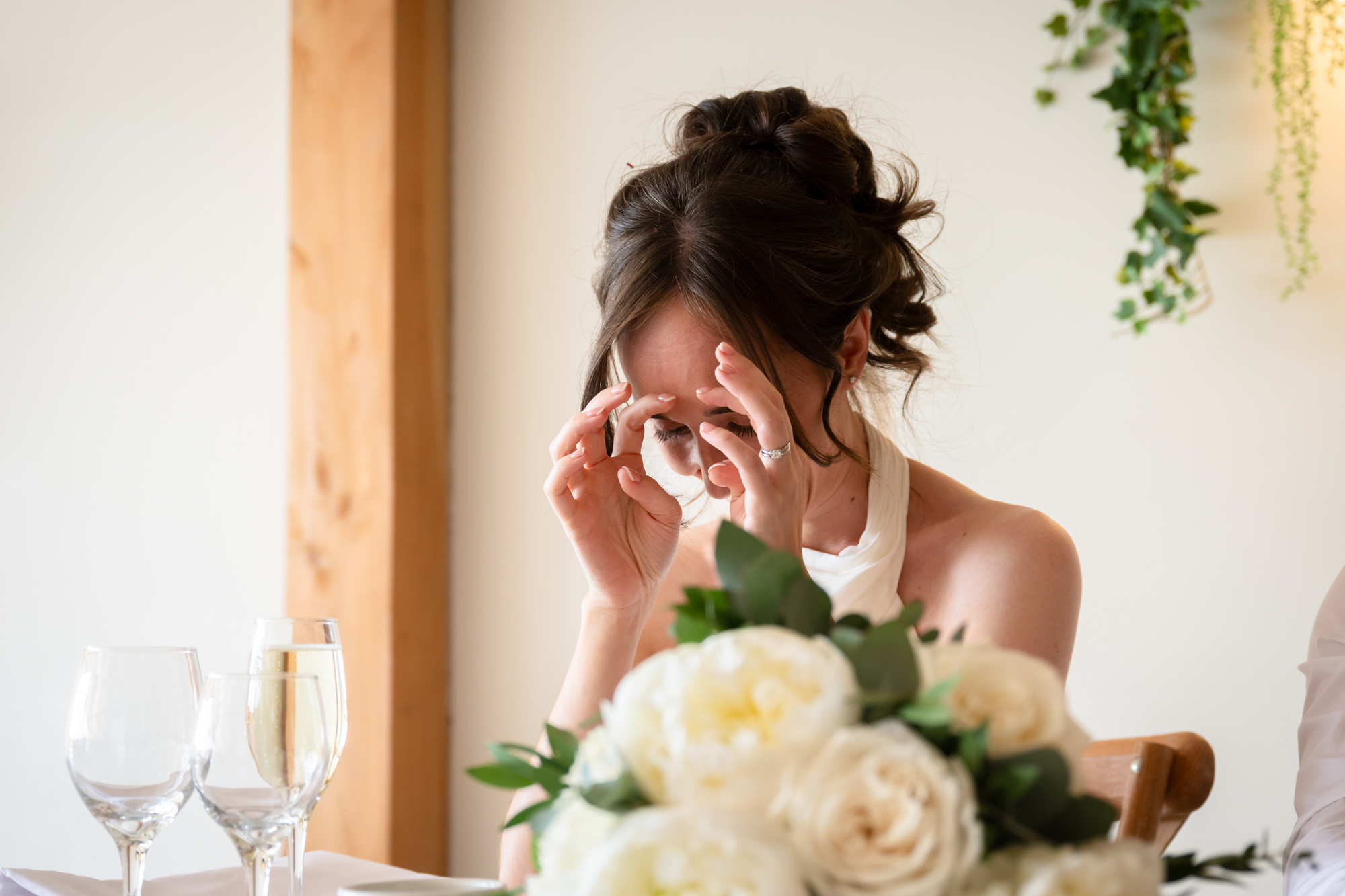 The bride looks embarrassed during the speeches at Hanbury Barns.