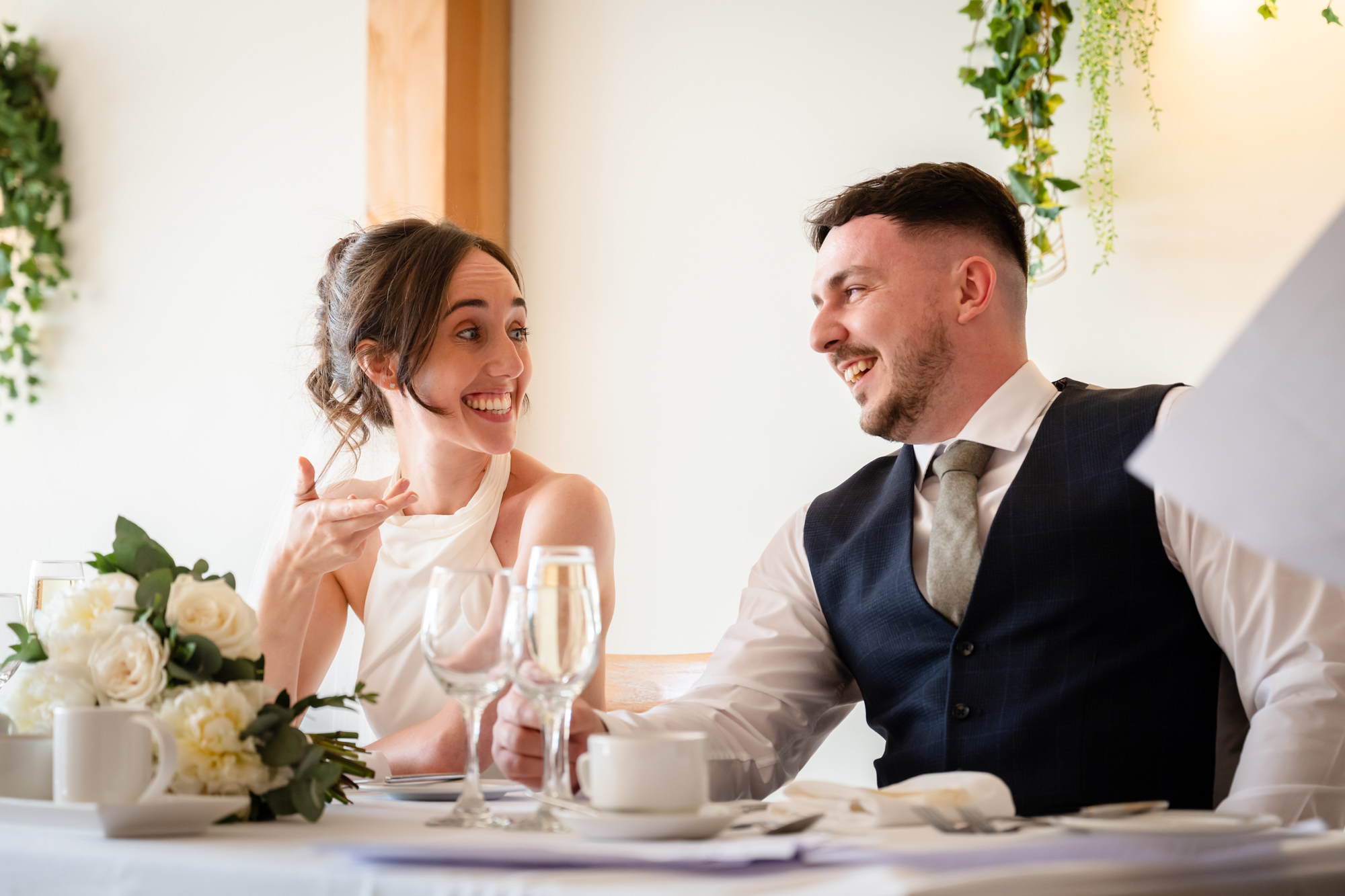 The bride and groom are smiling and looking at each other during the speeches at Hanbury Barns.