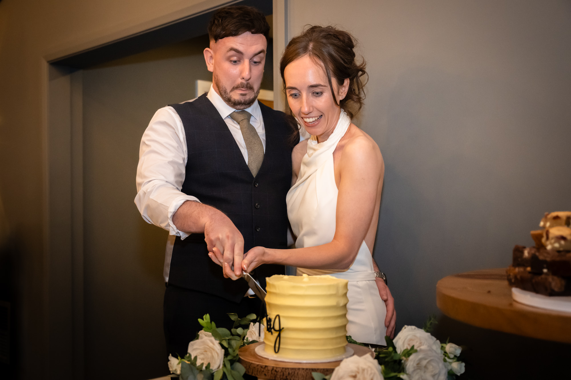 The bride and groom are captured cutting their two-tiered wedding cake at Hanbury Barns.