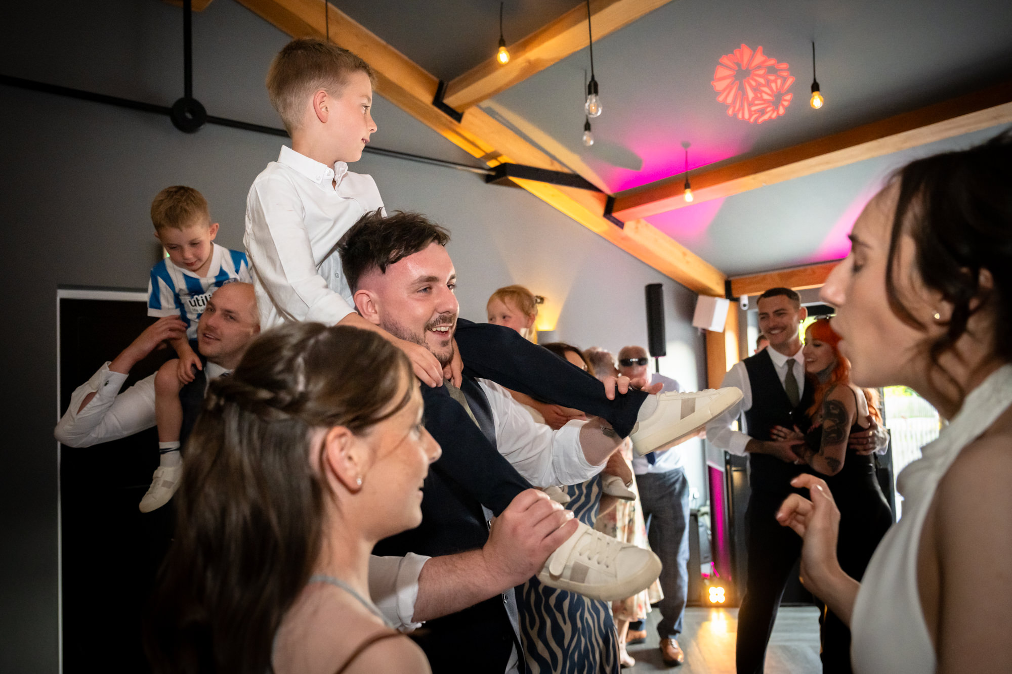 A group of guests are dancing together at the wedding party at Hanbury Barns.