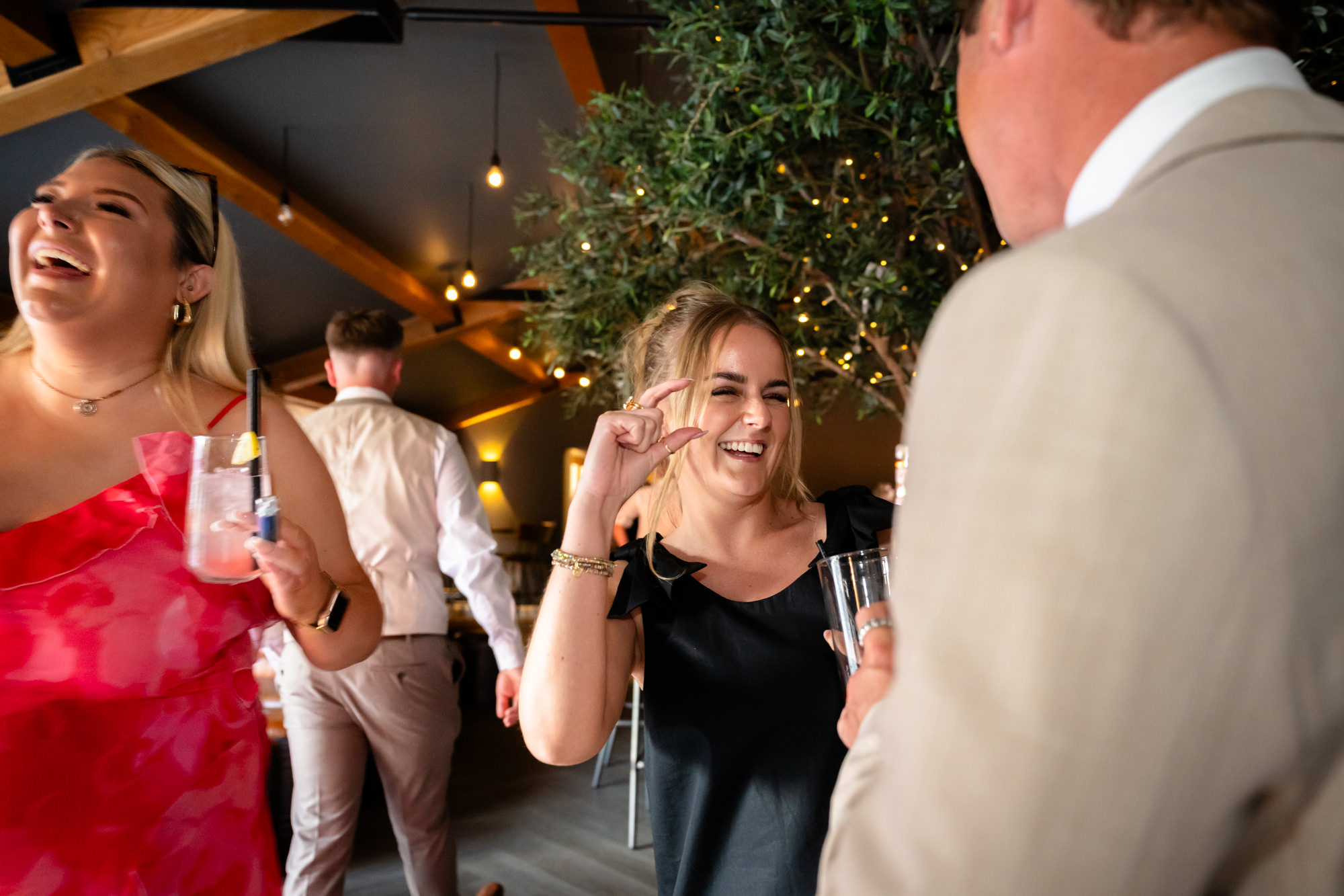 A woman in a black top is laughing as she dances at the wedding party at Hanbury Barns.