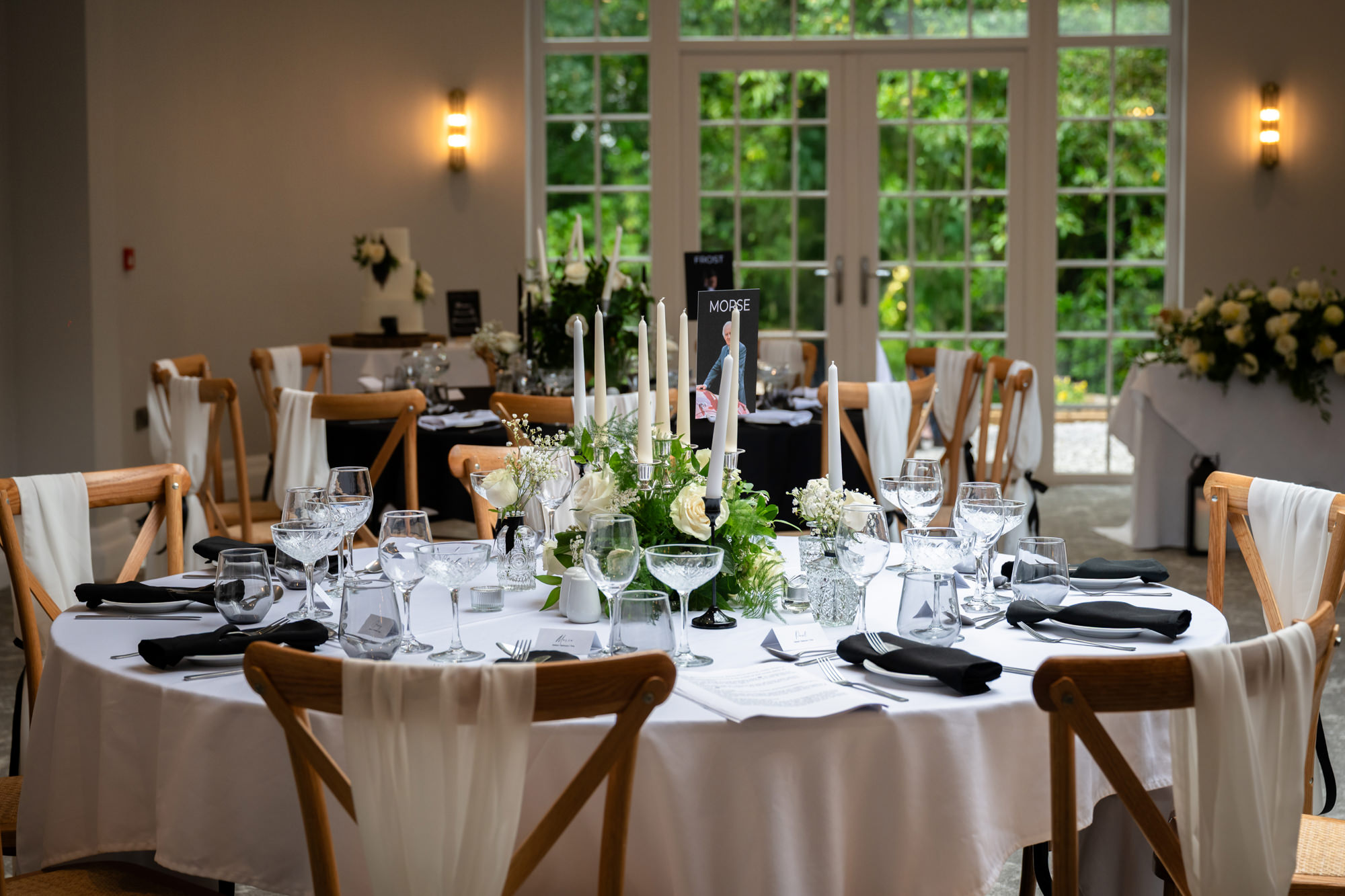 A large round table is set with a white tablecloth, glasses, and a floral centerpiece at Springbank Manor.