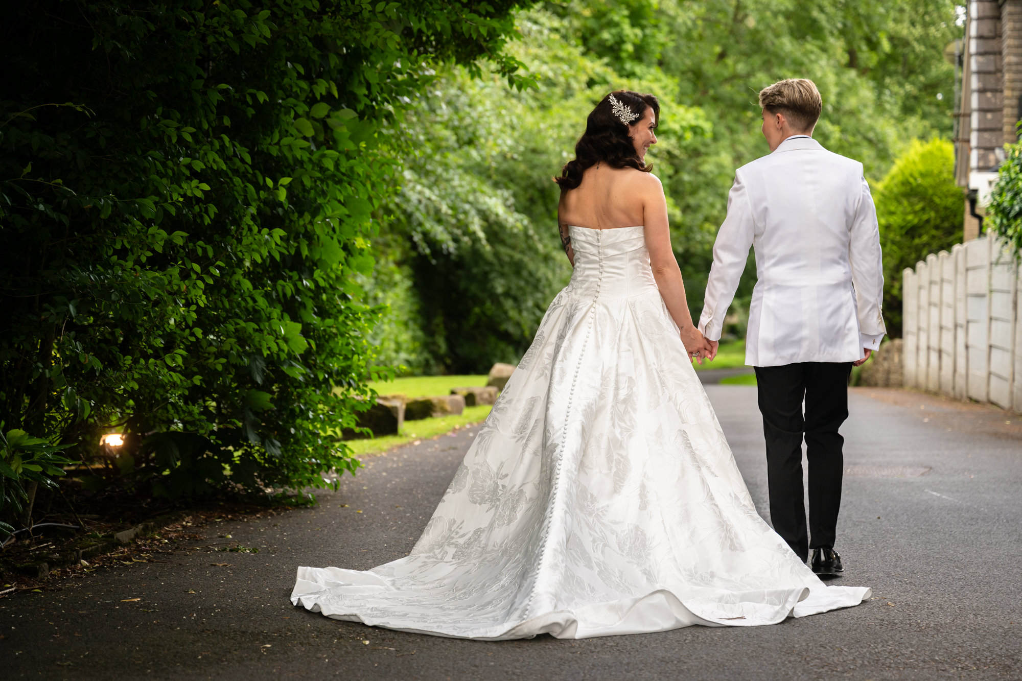 A portrait of the two brides, holding hands and walking away from the camera at Springbank Manor.