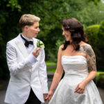 A portrait of the two brides, holding hands and smiling at each other at Springbank Manor.