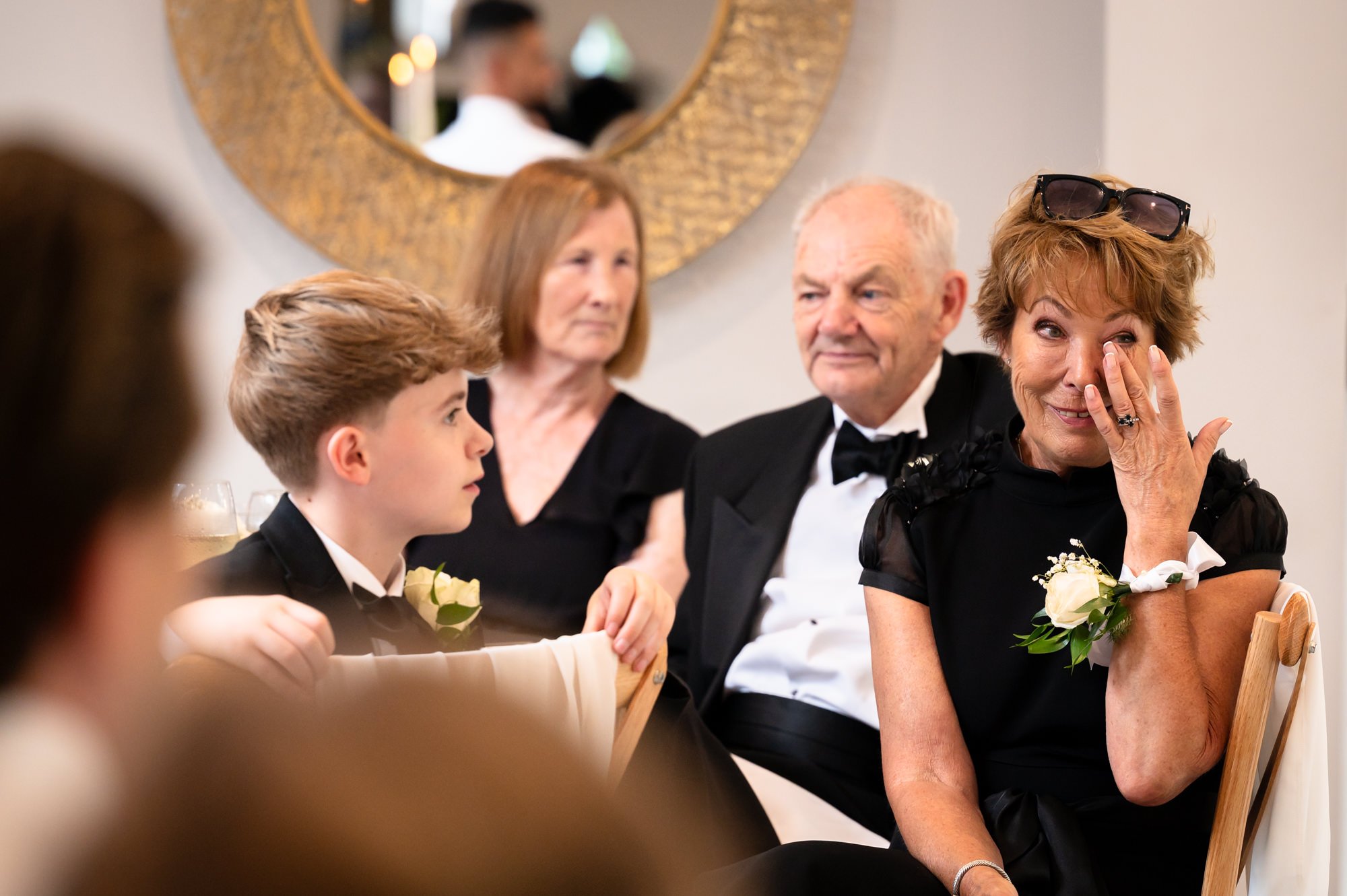 A group of people are seen in a candid photo at a table, with one of them wiping their face at Springbank Manor.