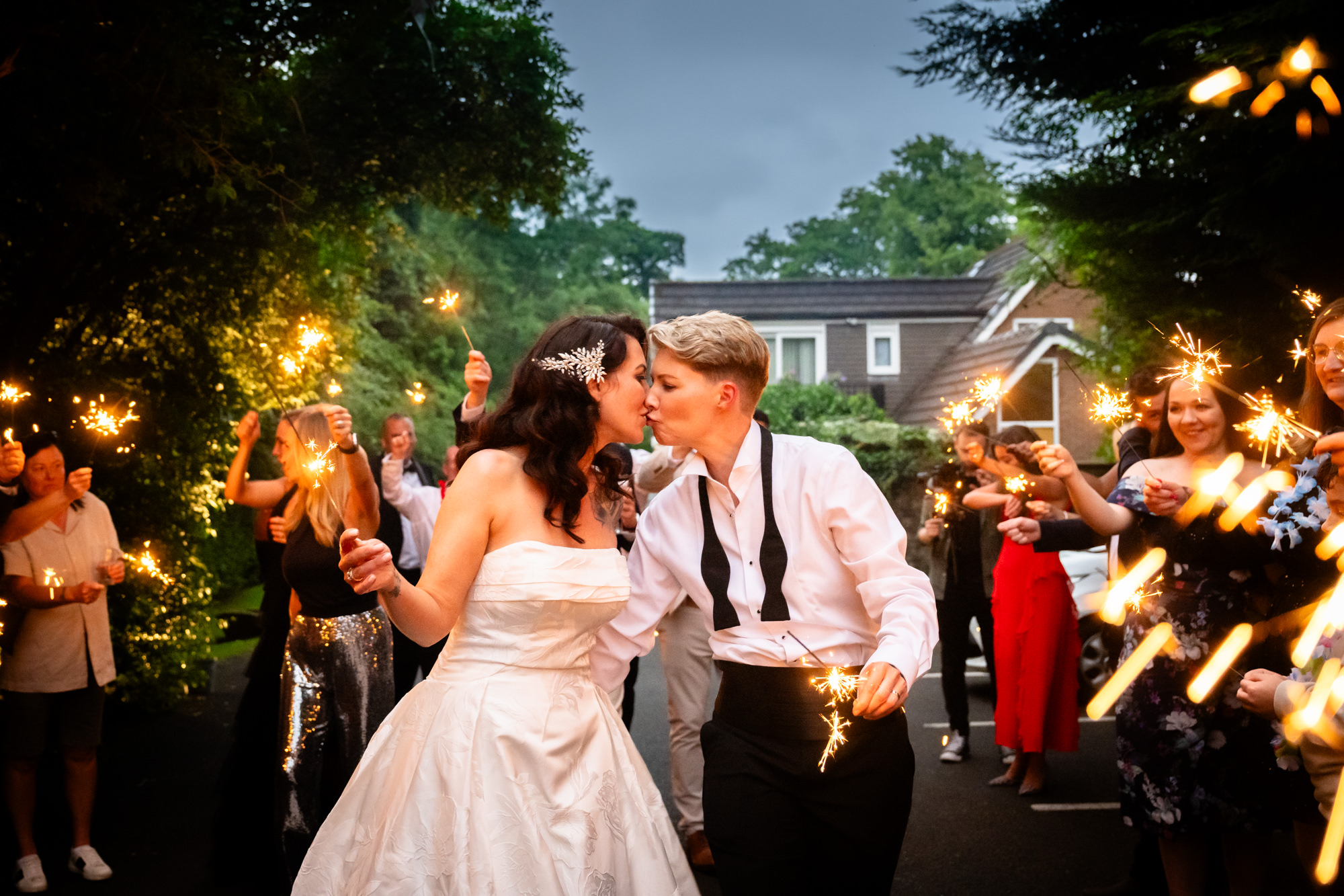 A group of people are holding sparklers and smiling in the evening at Springbank Manor.