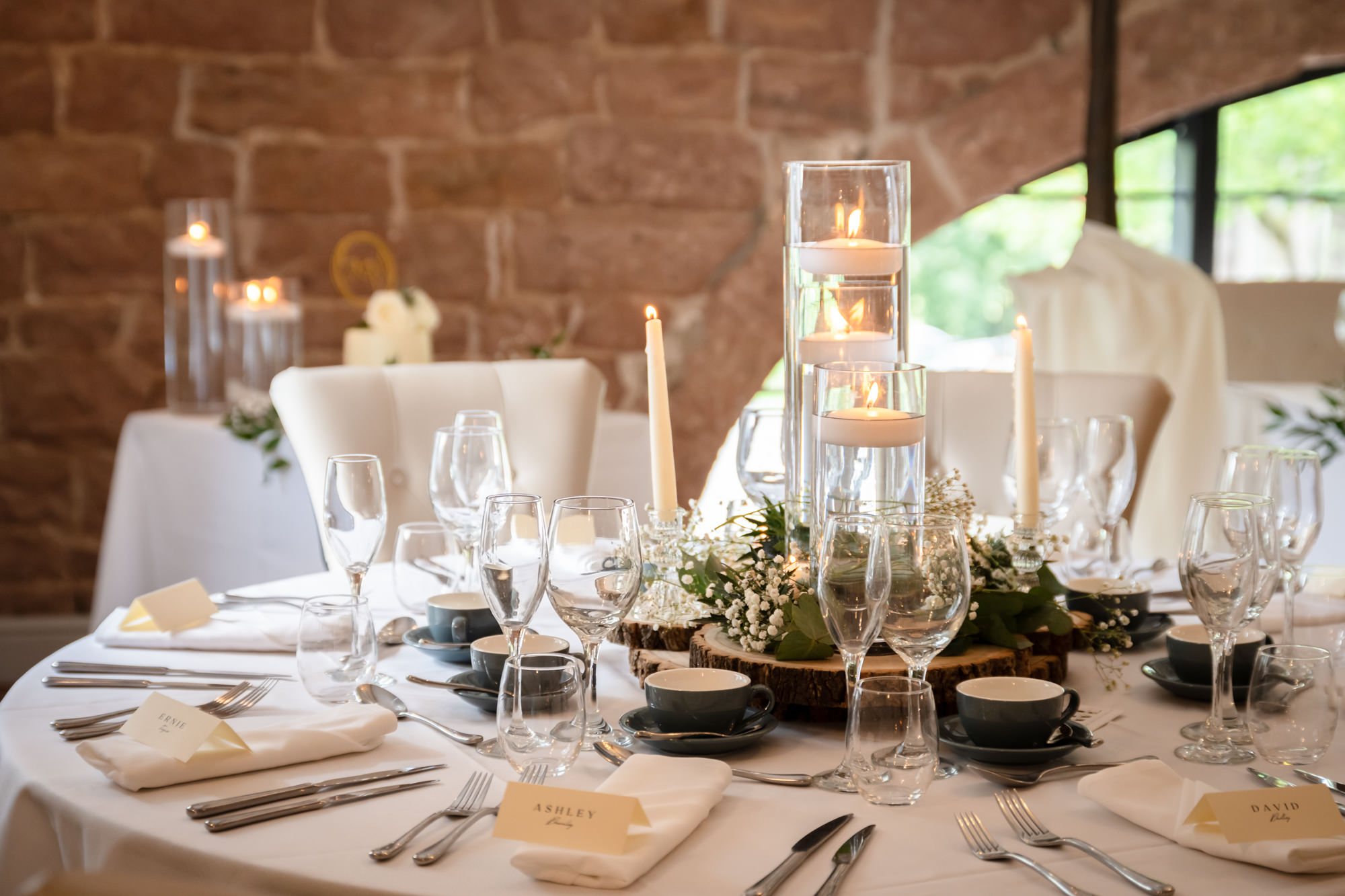 A closeup photo of a table decorated with floral centrepieces, candles.