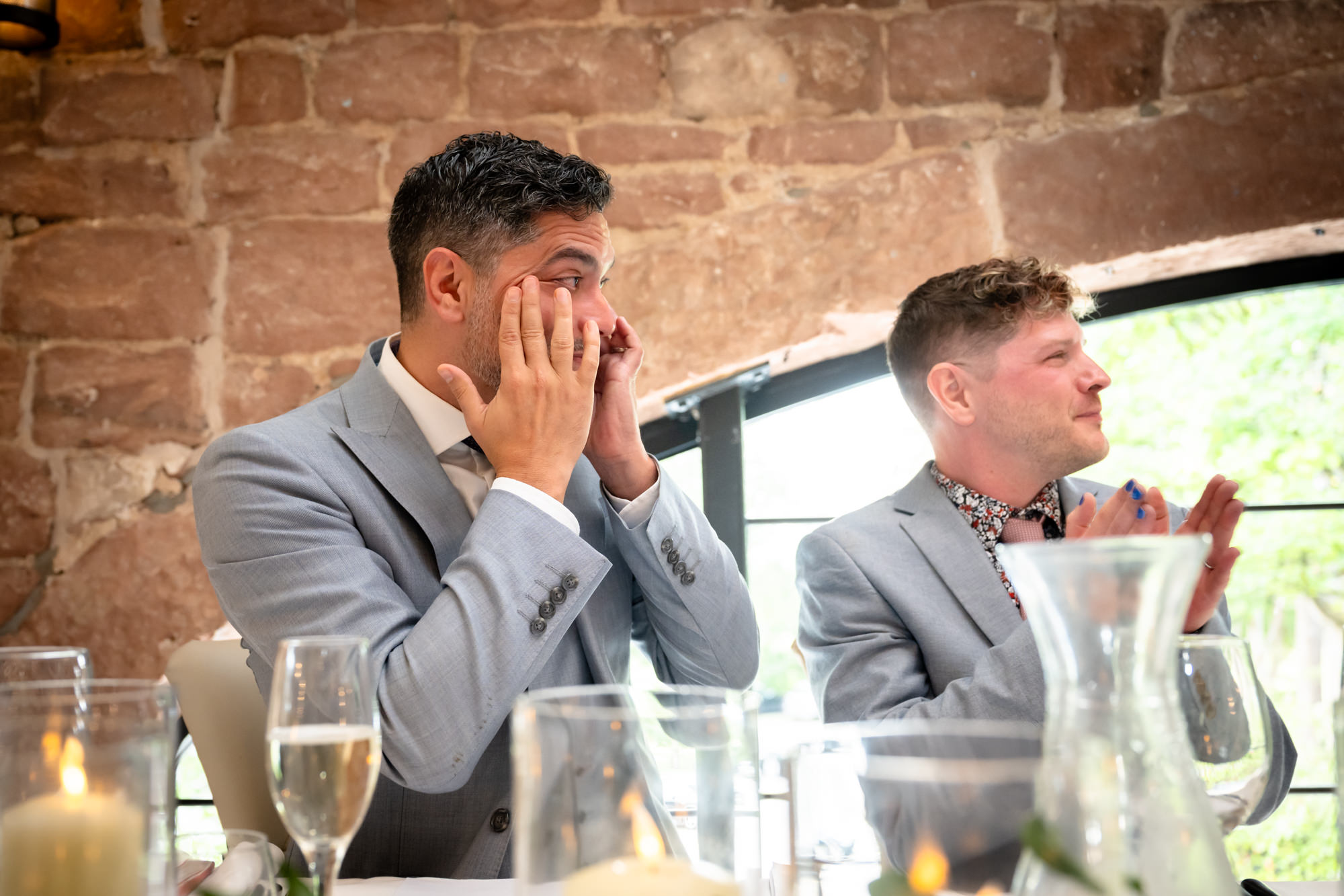 A man in a grey suit tries to hold his tears in