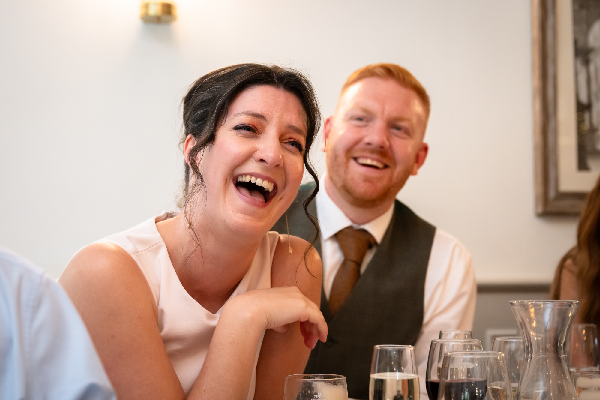 A woman with dark, curly hair laughs during the speeches at Allerton Manor