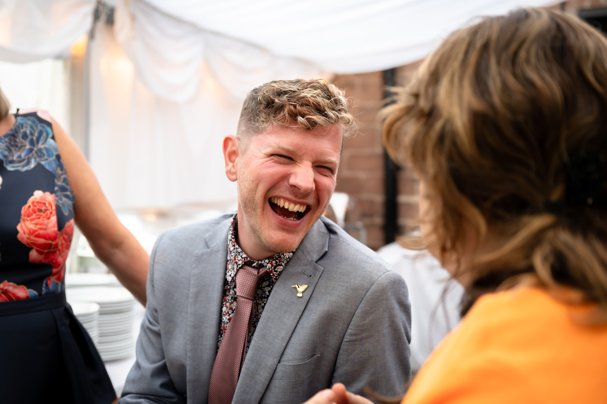 A guest laughs and smiles at another guest during the wedding reception.