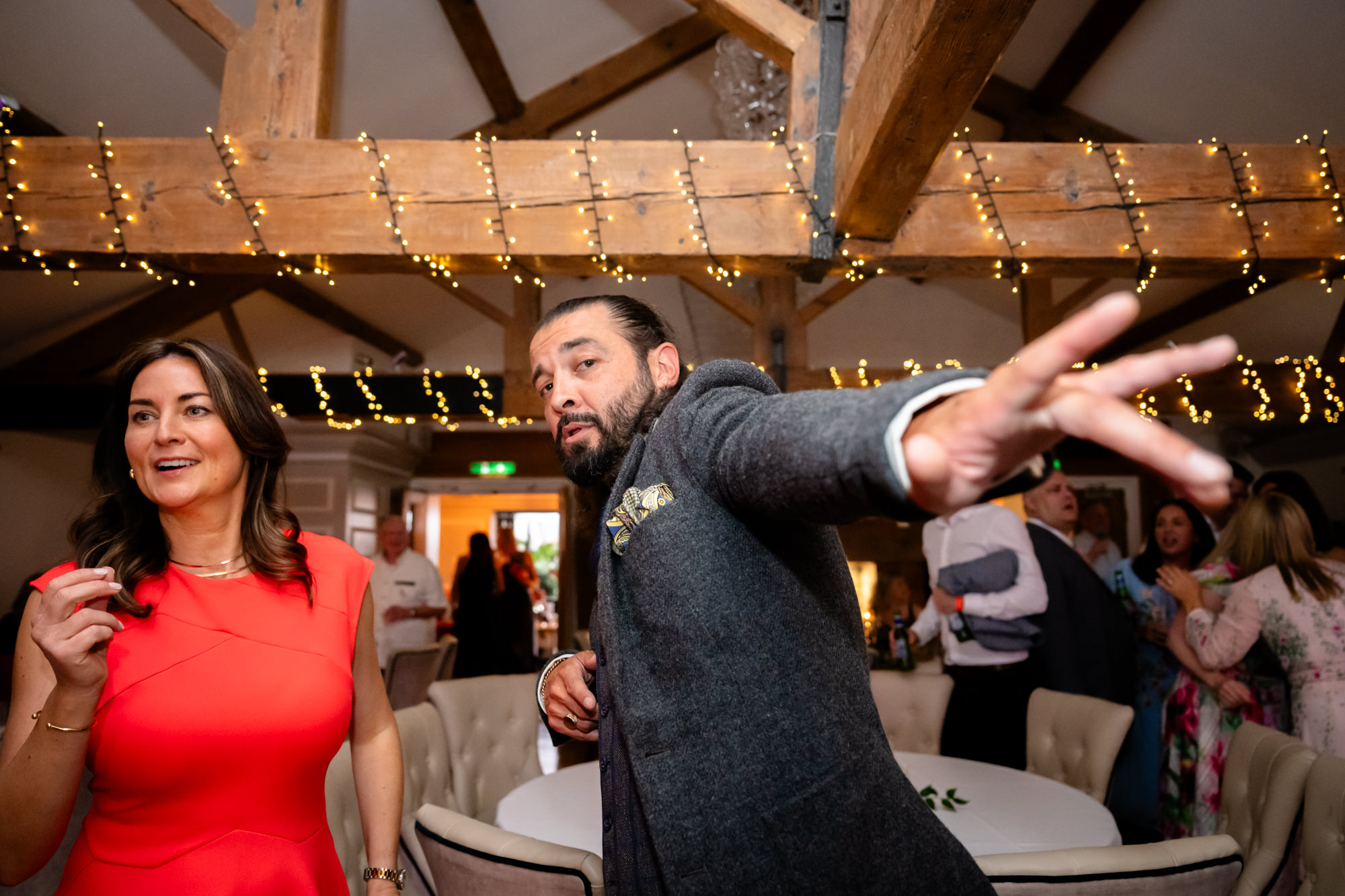 Wedding at Allerton Manor. A man in a dark grey suit dances with a woman in a red dress during the reception.