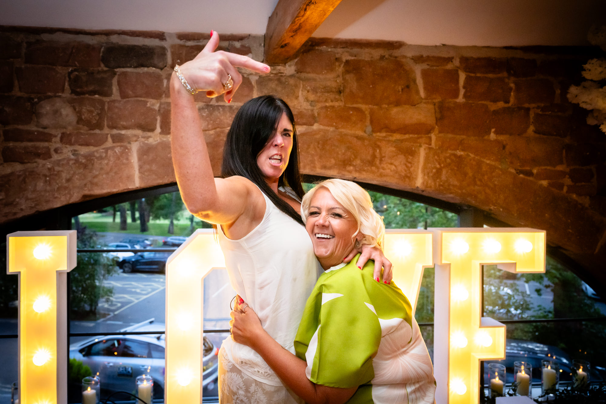 Two women dance together, one in a white top and the other in a green shirt.