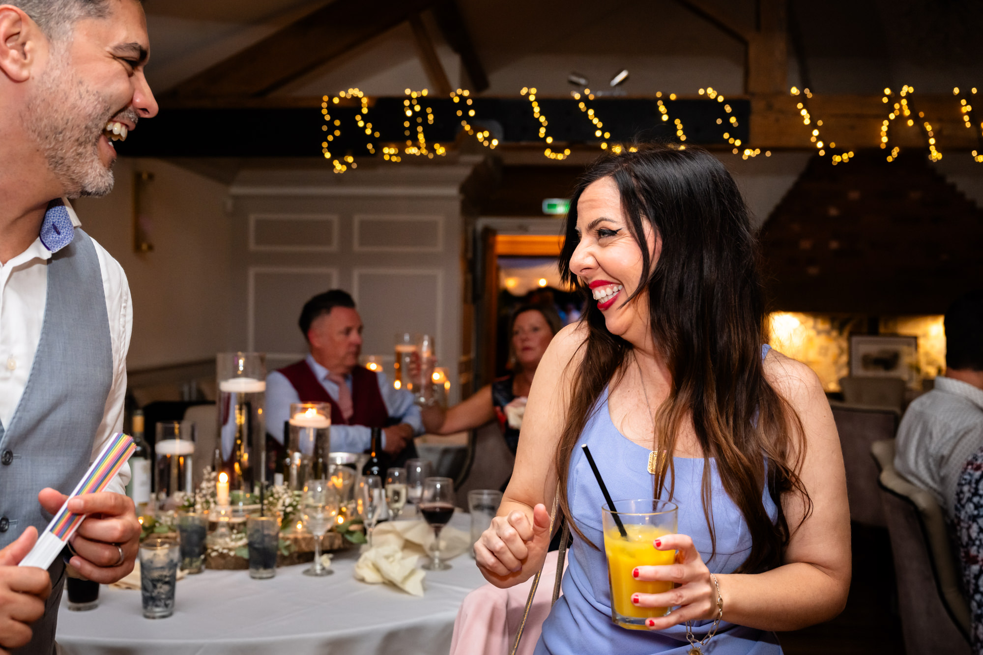 A woman with long dark hair holds a drink and dances during the party.